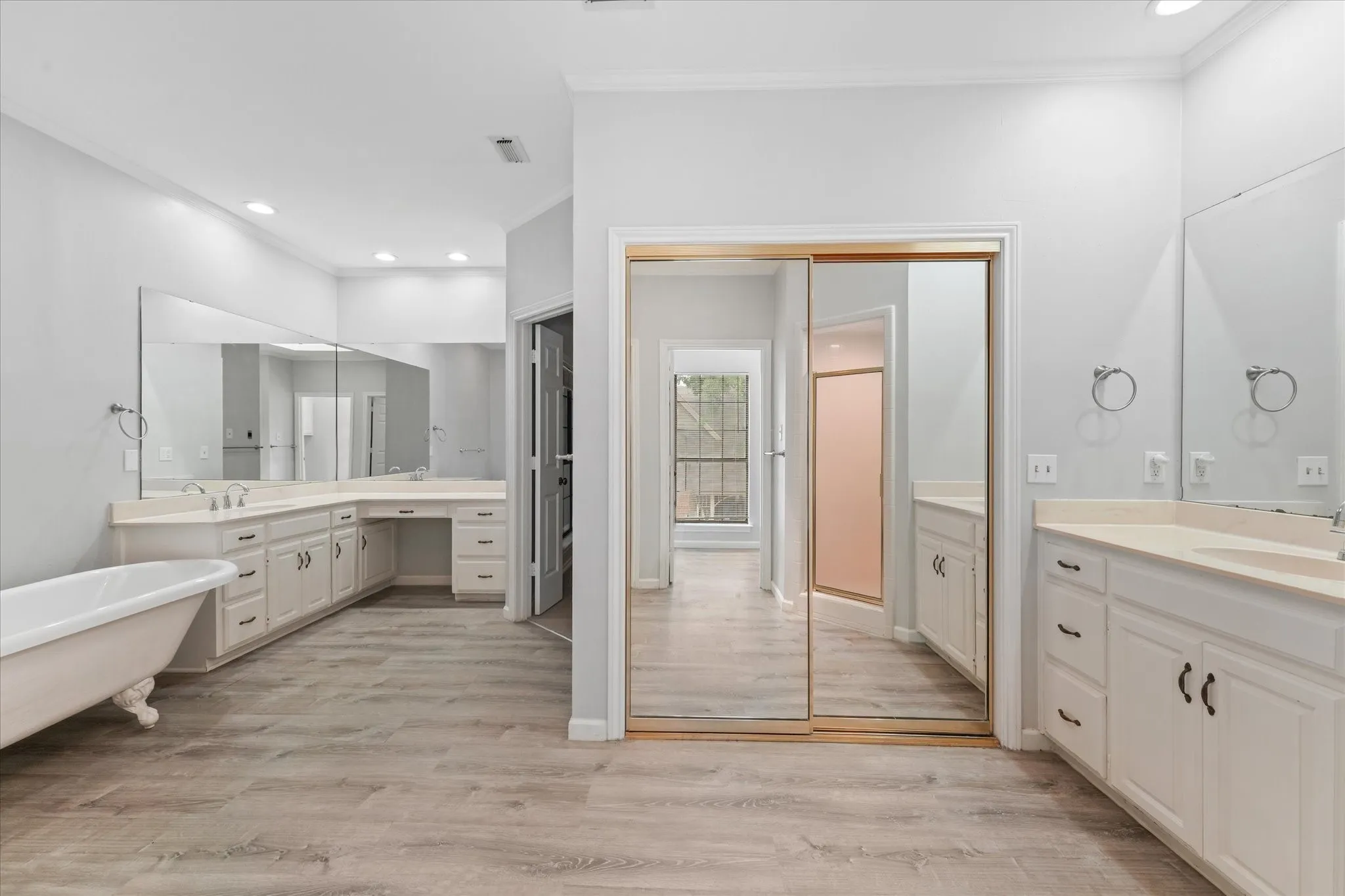Expansive primary bathroom with dual vanity areas, oversized mirrors, walk-in shower, and direct access to the spacious primary suite.