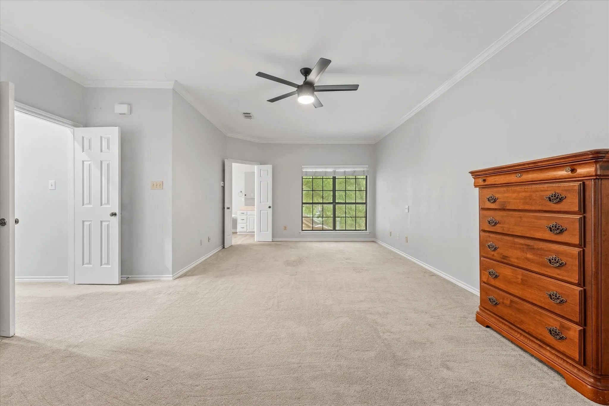 Oversized primary bedroom with neutral paint, updated ceiling fan, abundant natural light, and flexible space for a sitting area or home office setup.