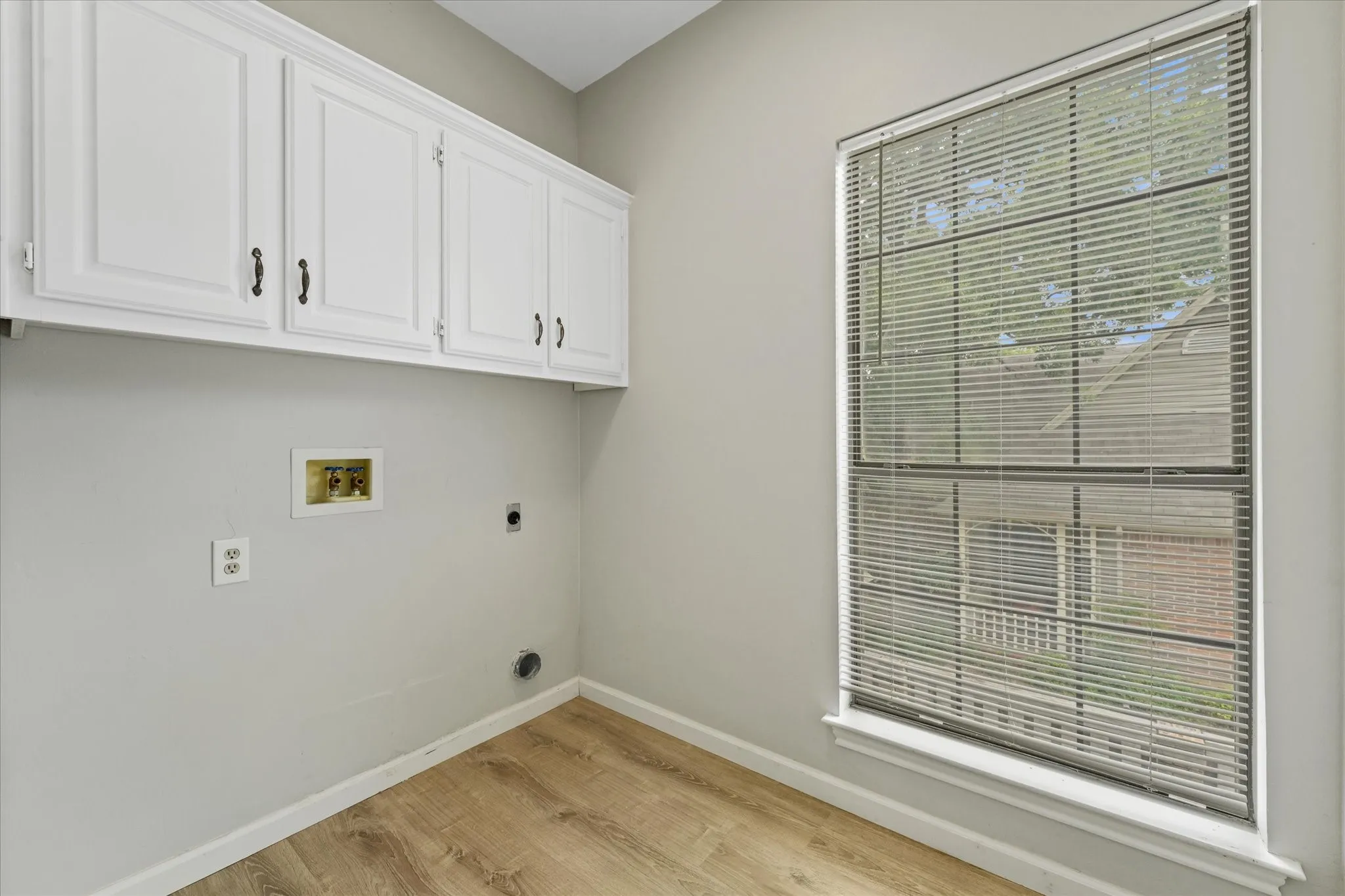 Dedicated upstairs laundry room with built-in cabinetry, storage space, and natural light from oversized window.