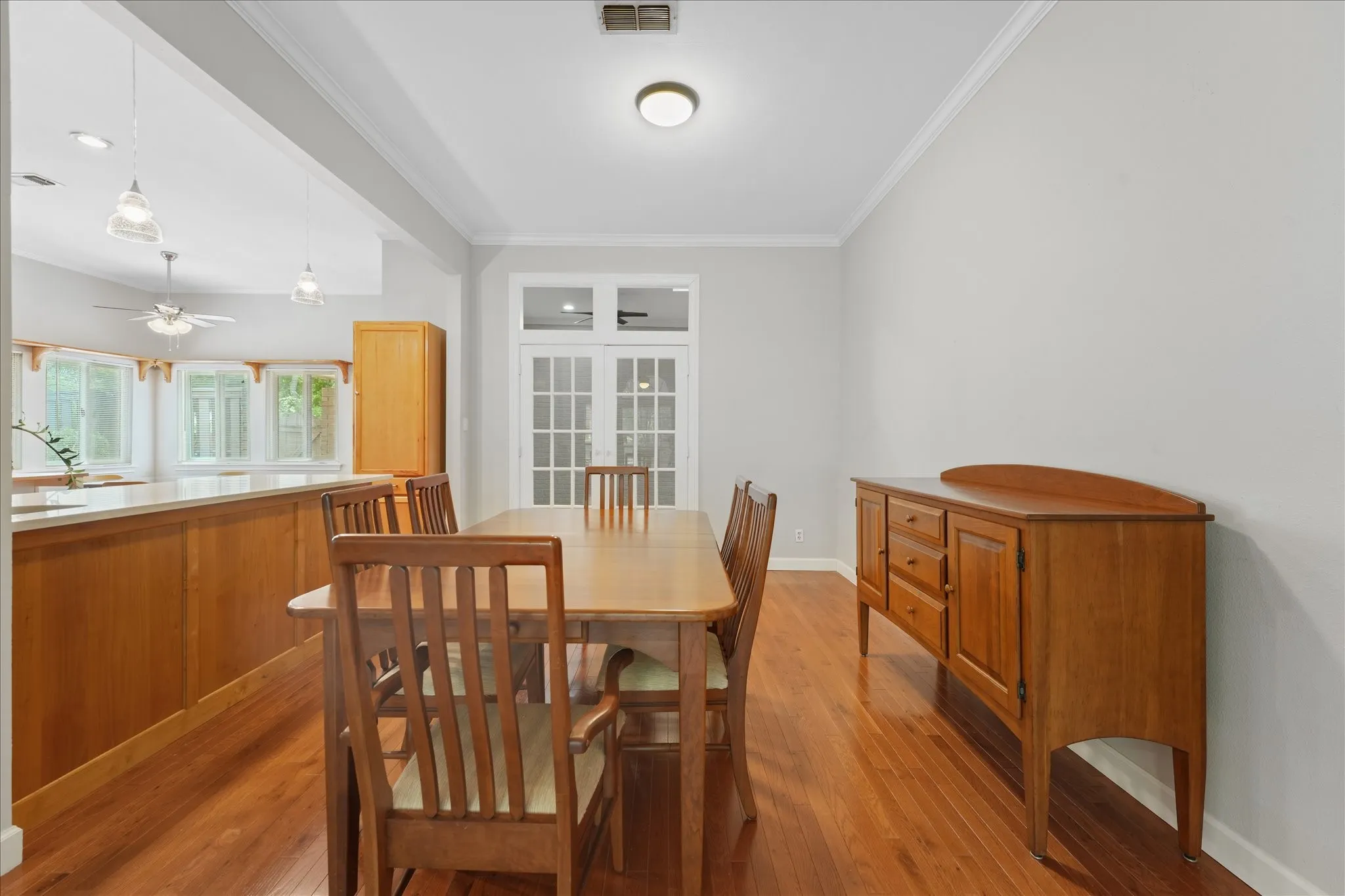 Dedicated dining area with hardwood floors, open-concept layout, and French doors leading to a flexible bonus room or home office space.