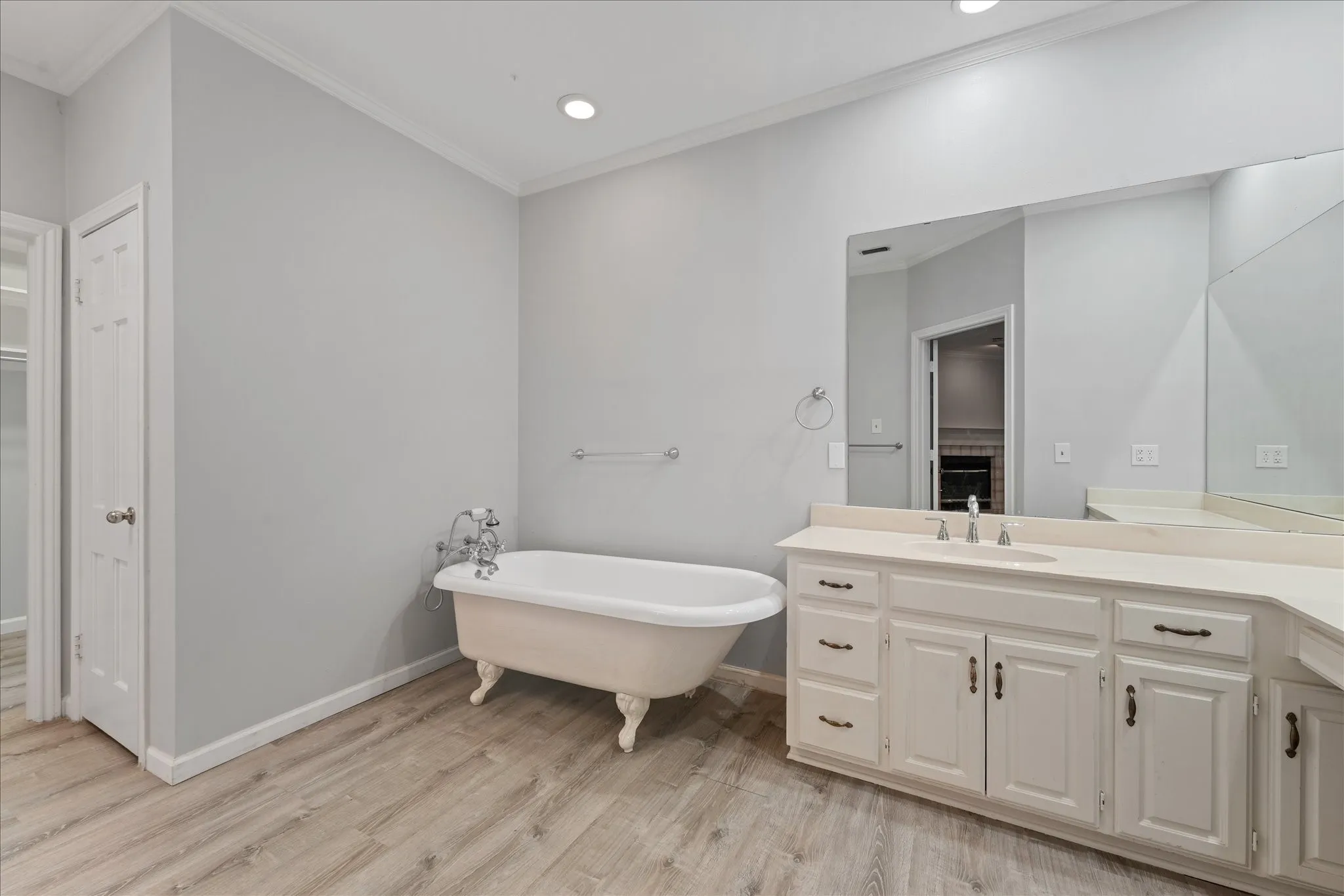 Large primary bathroom with freestanding clawfoot soaking tub, oversized vanity, updated flooring, and extensive counter space.