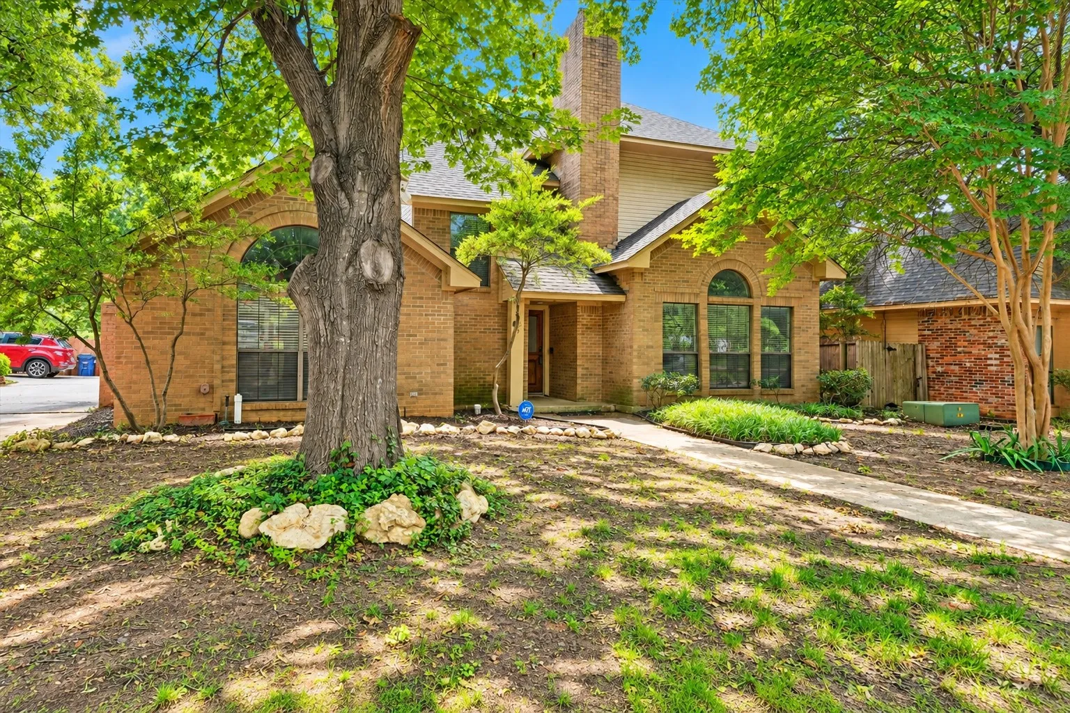 Two-story traditional home with updated front door, arched windows, and shaded front yard on Highland Park Circle in South Denton.