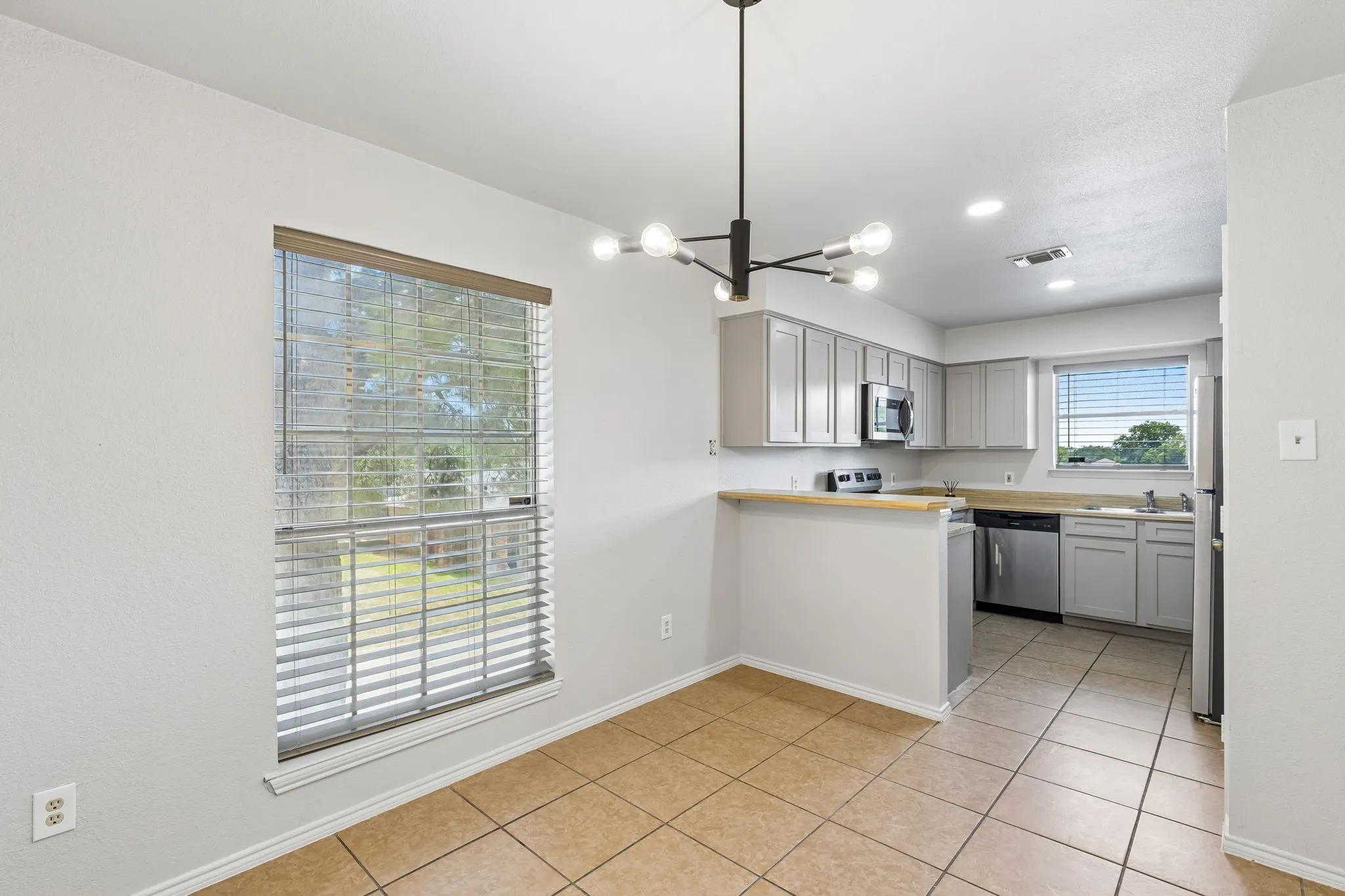 Kitchen featuring gray cabinetry, stainless steel appliances, and a tiled floor