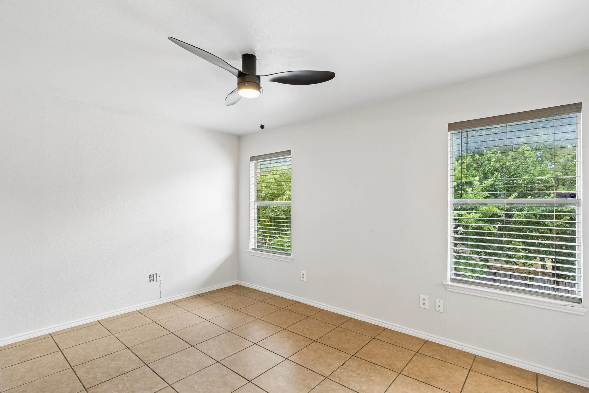 Recessed lighting, ceiling fan, two windows with blinds, tiled flooring, and neutral wall tones