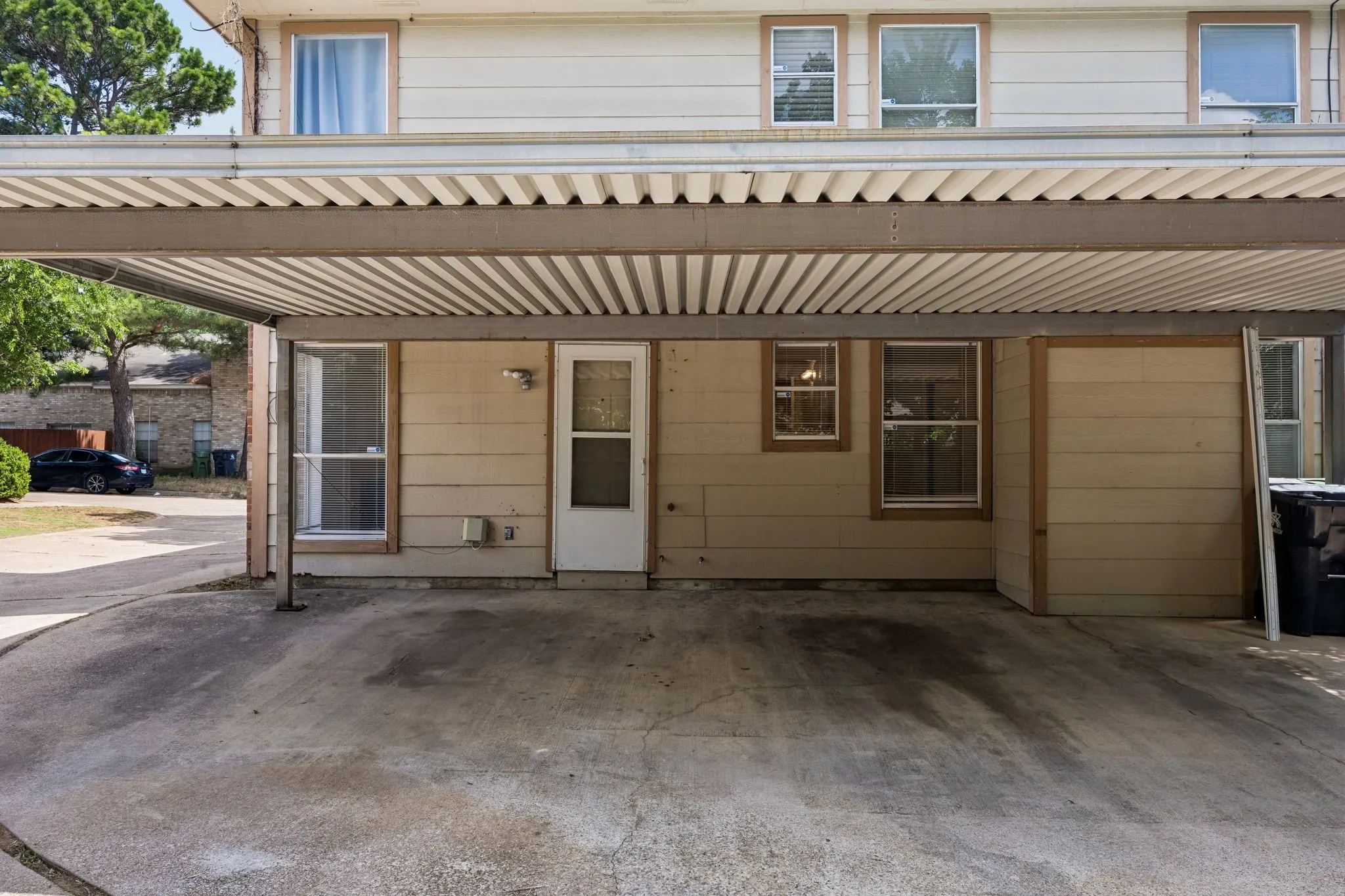 Carport providing covered parking, featuring a corrugated metal roof and support columns