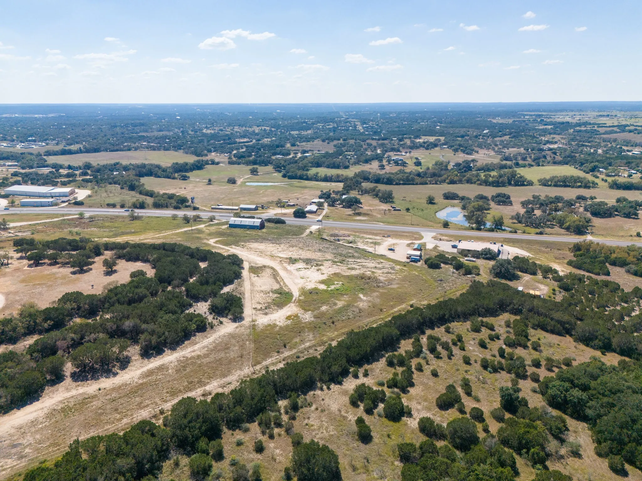 Expansive land with varied terrain, including undeveloped areas and scattered trees