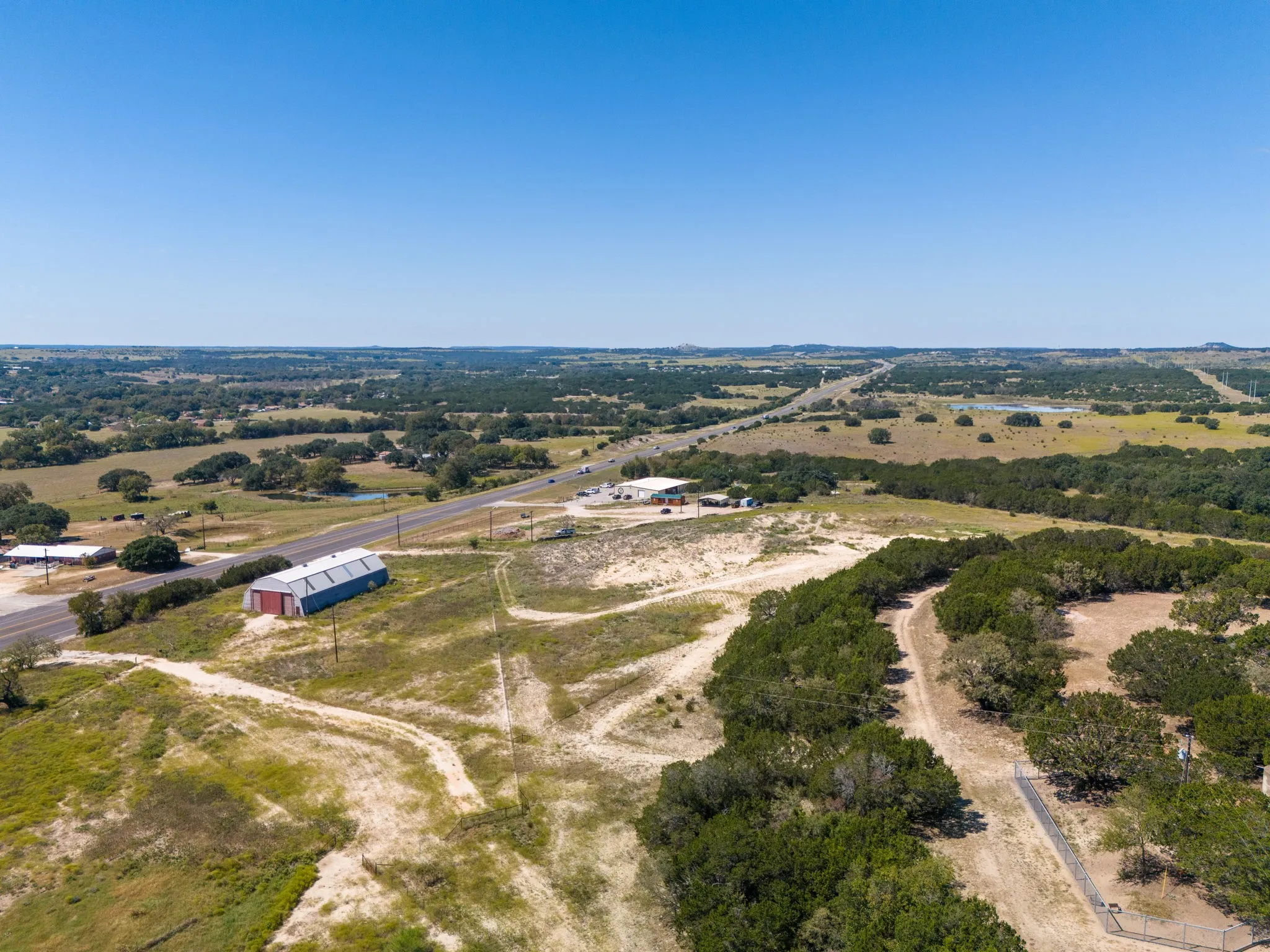 Expansive open land with a large metal-clad building, surrounded by mature trees and natural vegetation