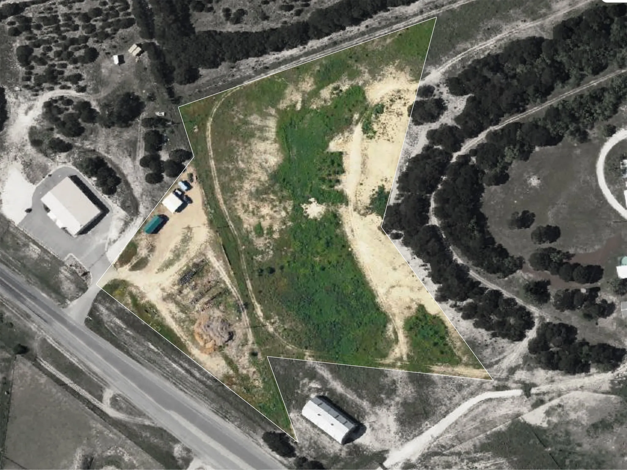Expansive lot featuring varied terrain, a grassed area, and surrounding tree coverage