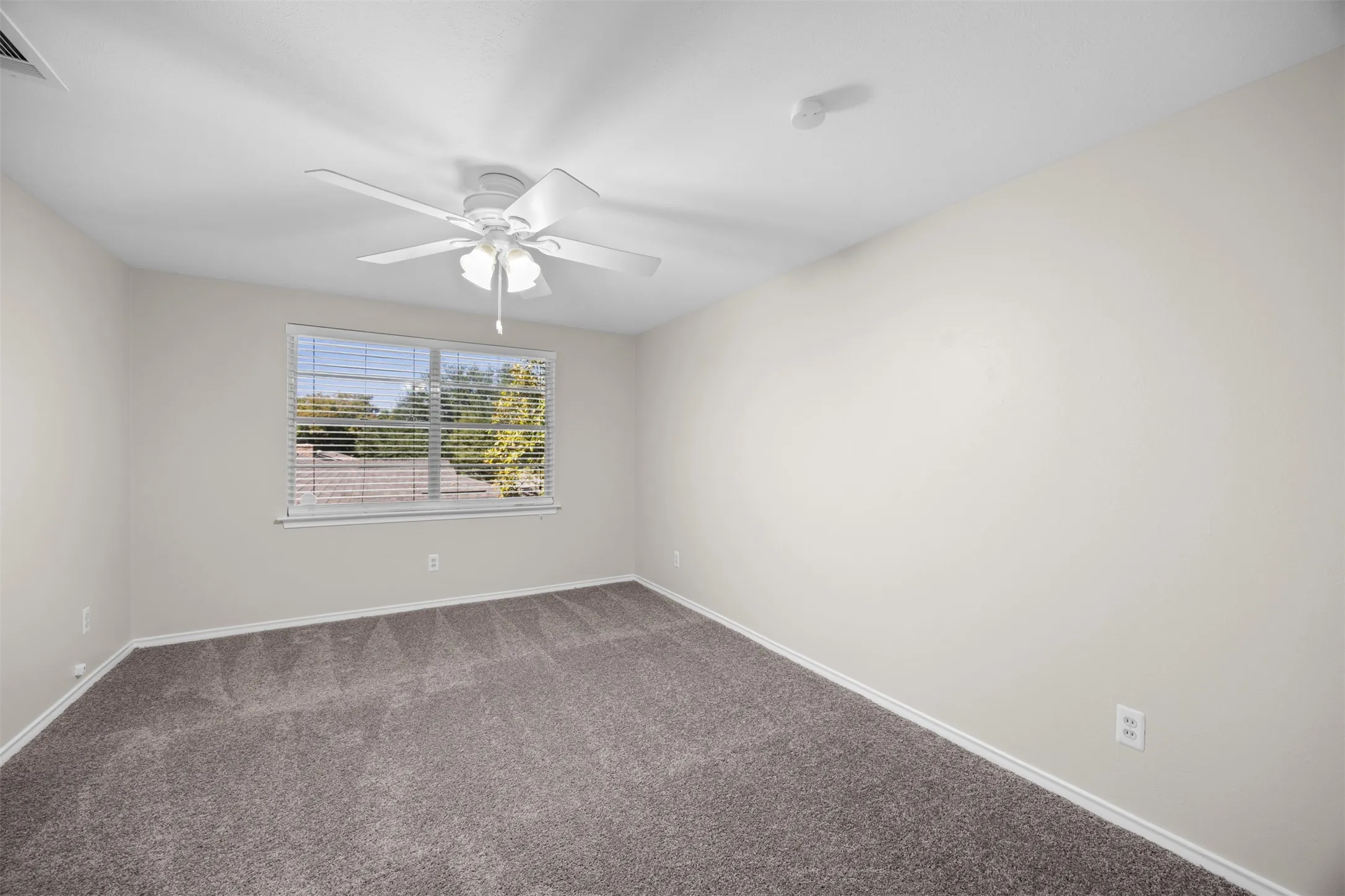 Carpeted flooring, neutral wall tones, window with horizontal blinds, and a ceiling fan with integrated lighting