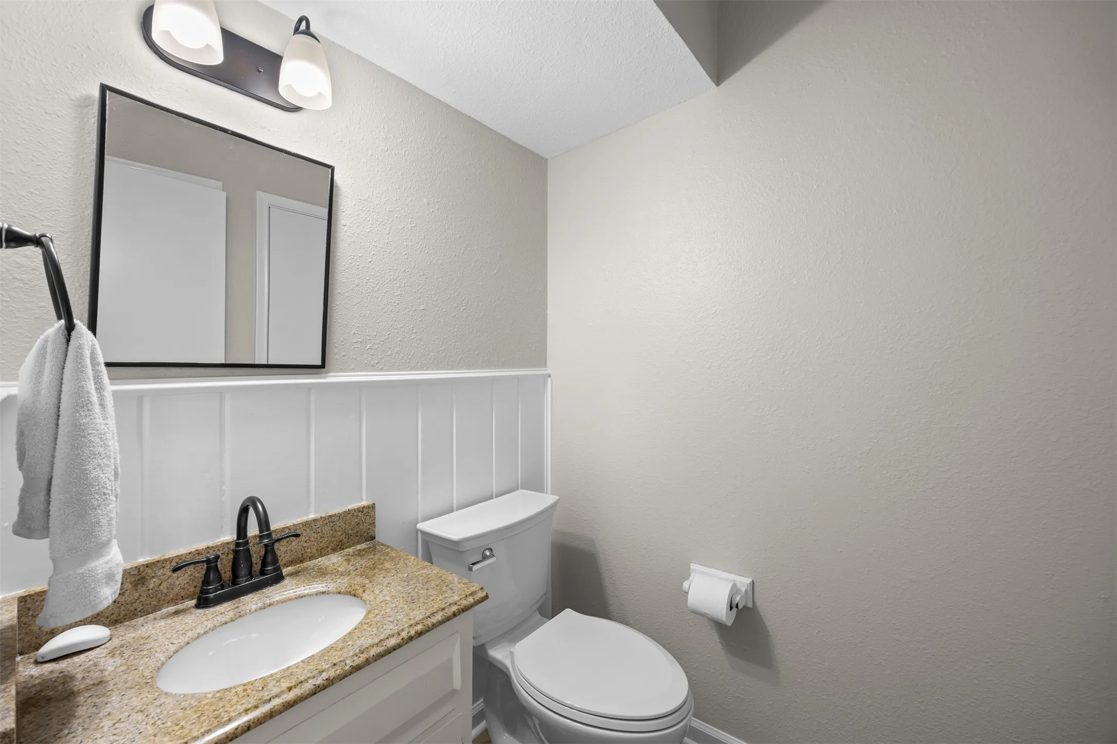 Vanity with stone-finish countertop, undermount sink, and dark bronze-finish faucet