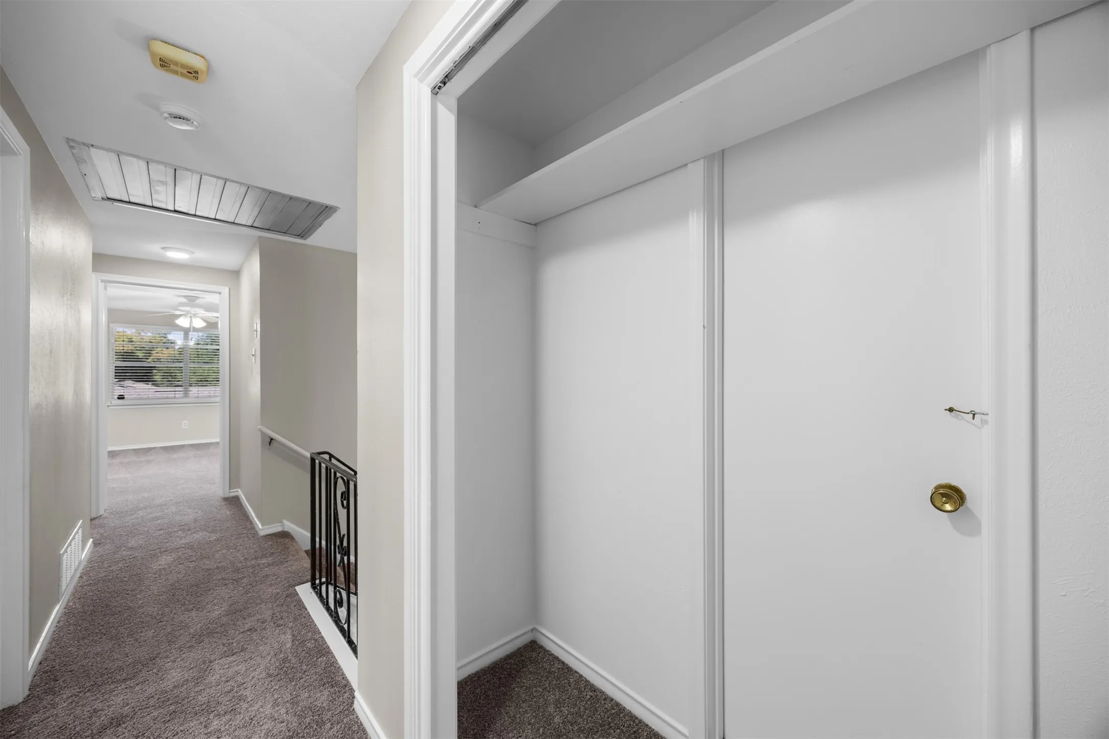Hallway with carpeted flooring, white walls, and a built-in closet with sliding doors