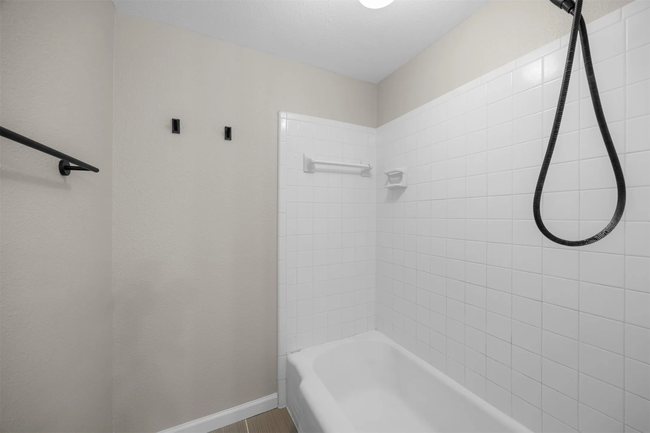 White subway tile surround with a built-in soap dish, complete with a white bathtub and handheld shower fixture