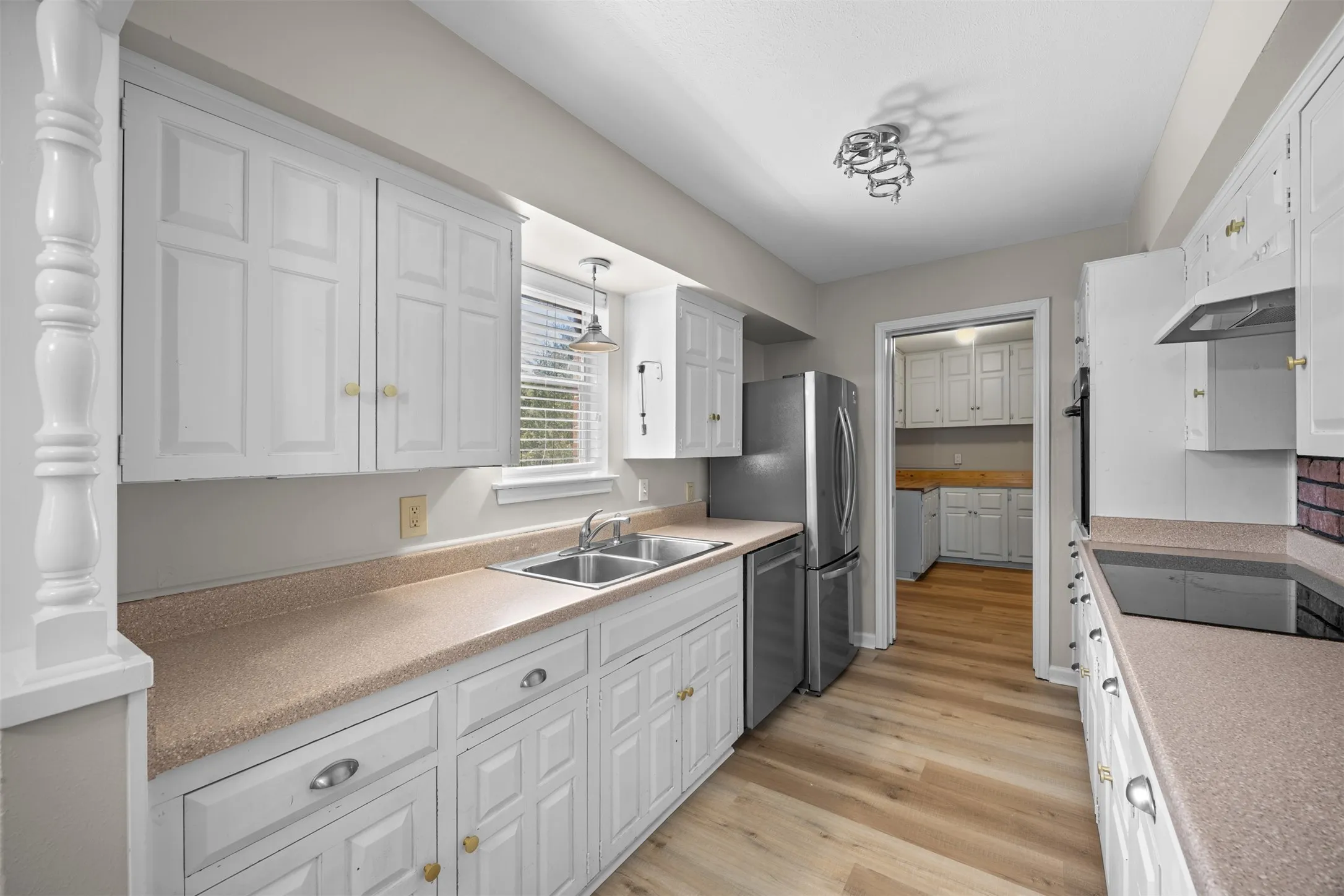 Kitchen featuring white paneled cabinetry, light-toned countertops, and wood-finish flooring