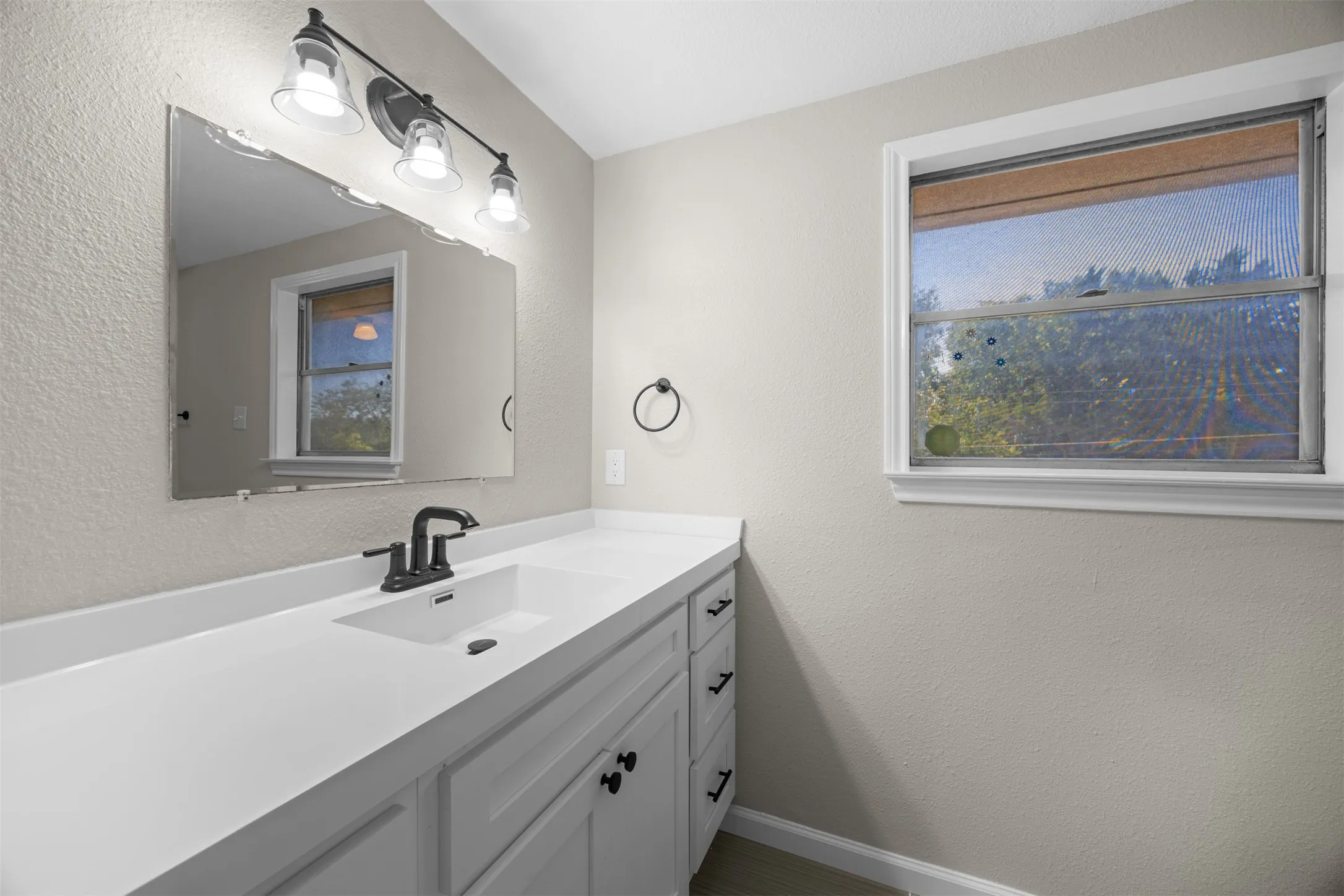 White vanity with black hardware, integrated sink, and white countertop