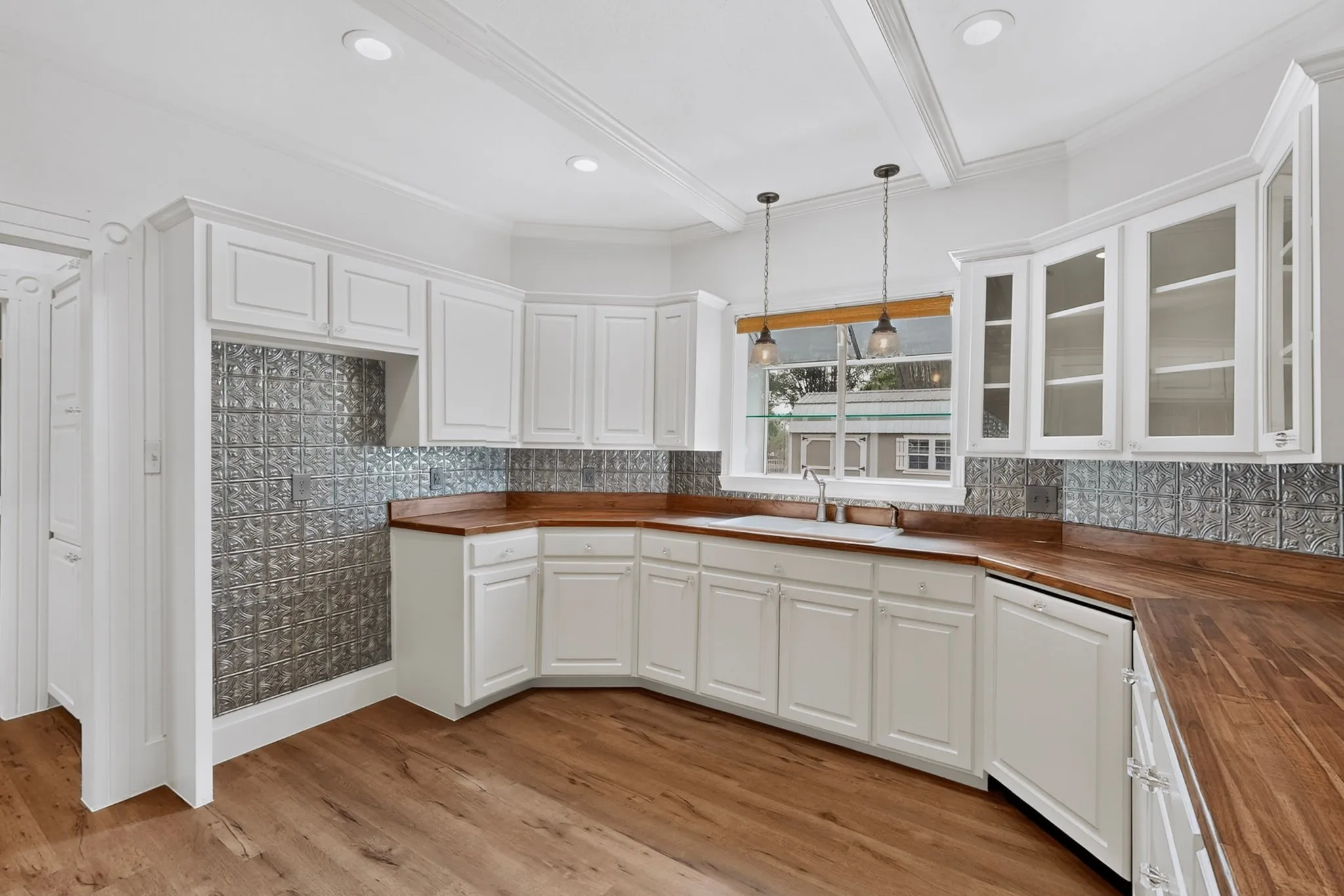 White cabinetry, pressed tin backsplash, wood-finish flooring, wood countertops, and recessed lighting