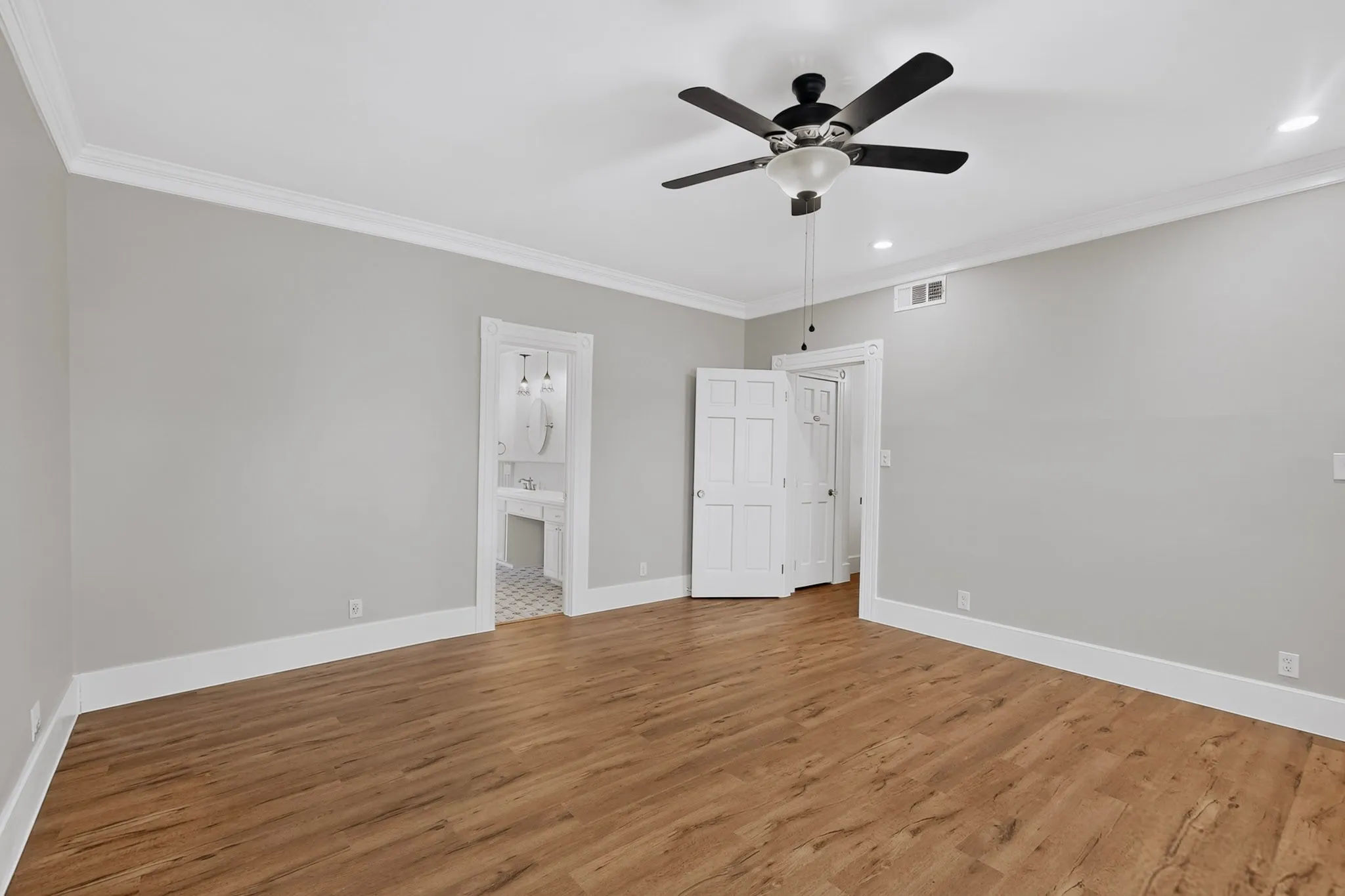 Wood-finish flooring, crown molding, ceiling fan, recessed lighting, and panel doors
