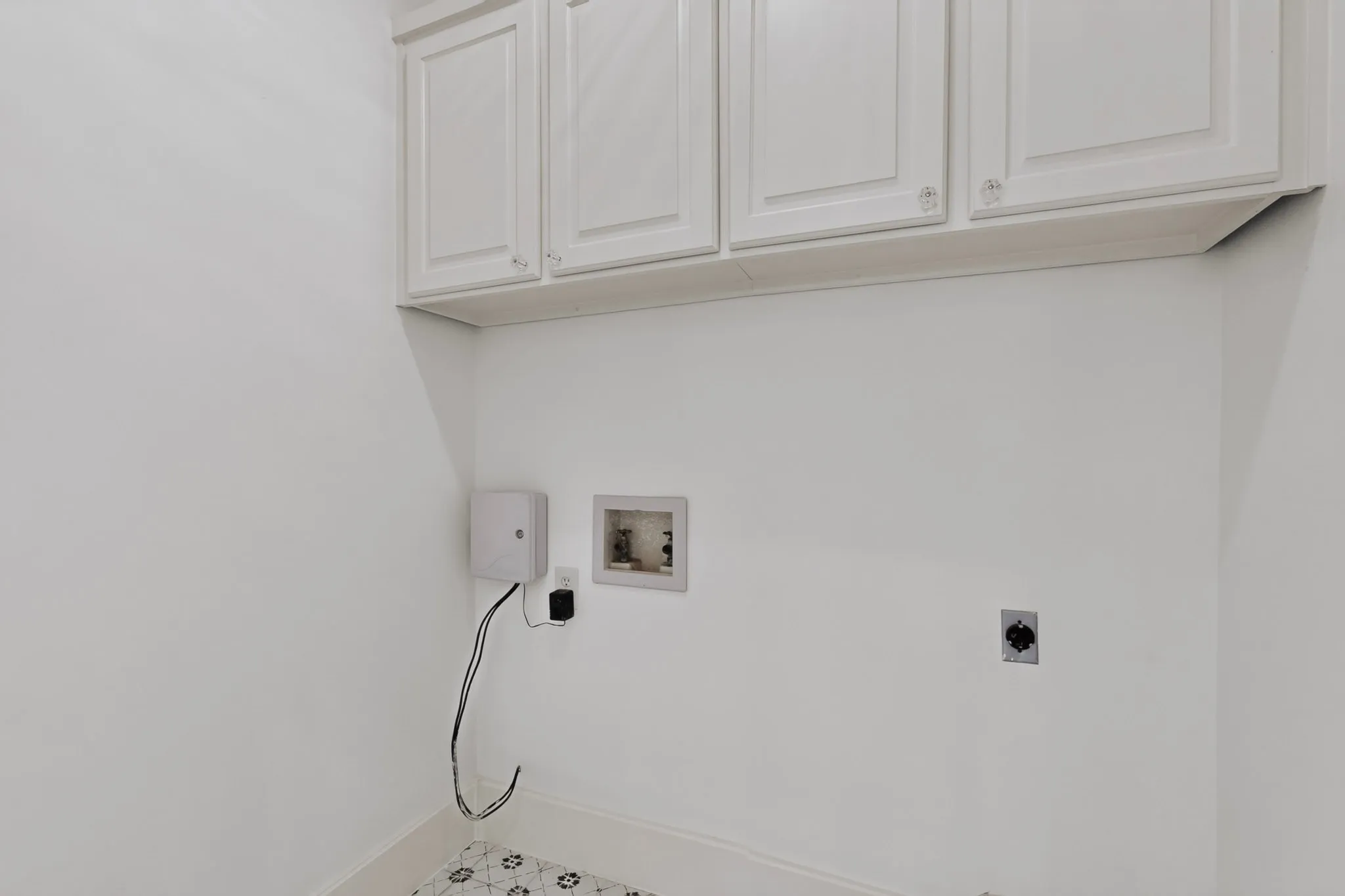 White cabinetry, patterned floor tiles, light-toned walls