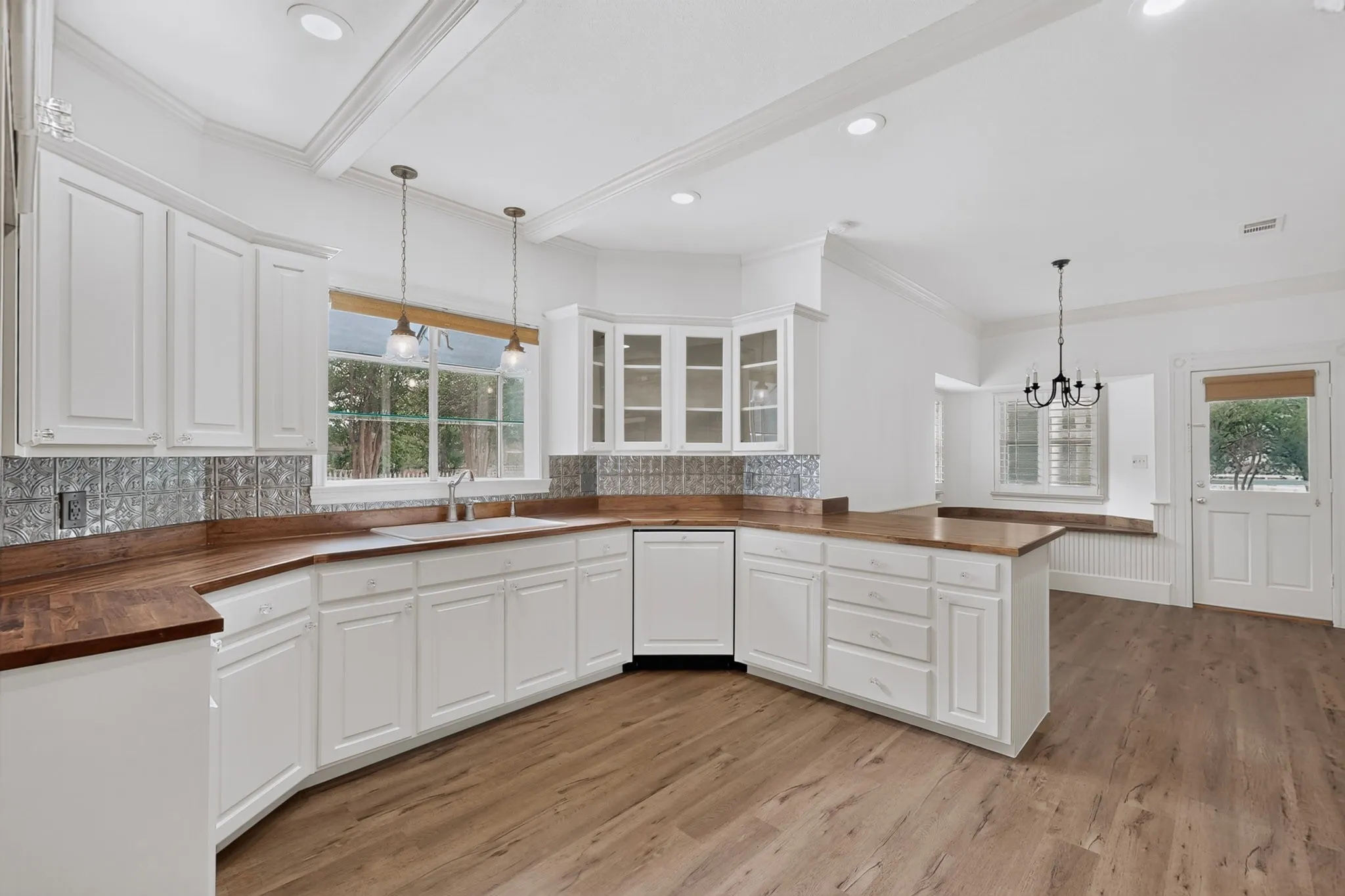 White shaker-style cabinetry with wood-finish countertops, stainless steel sink, and a patterned backsplash