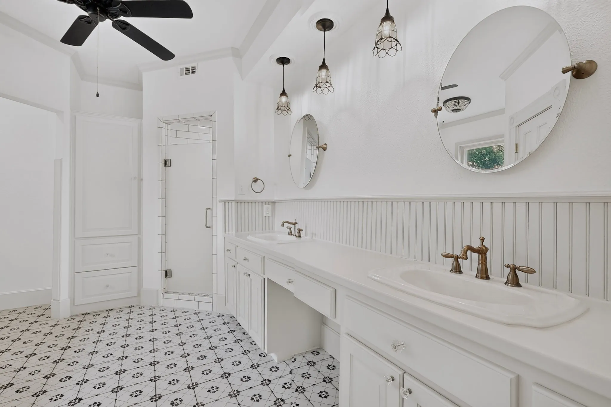 Dual vanity with integrated sinks, custom white cabinetry, and beadboard wainscoting