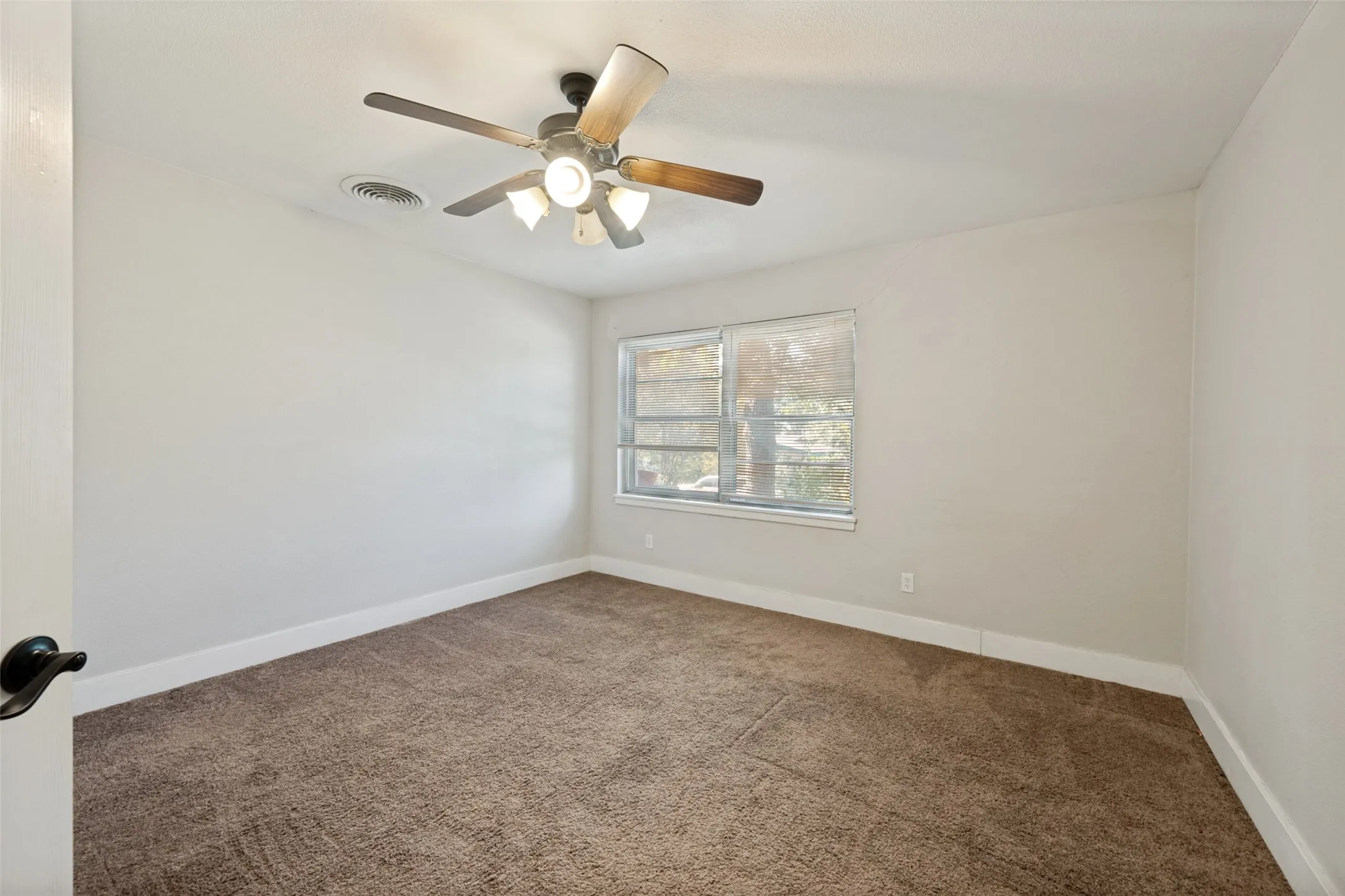 Neutral wall finishes, textured carpeting, contemporary ceiling fan with lighting, white trim, and a window with exterior visibility