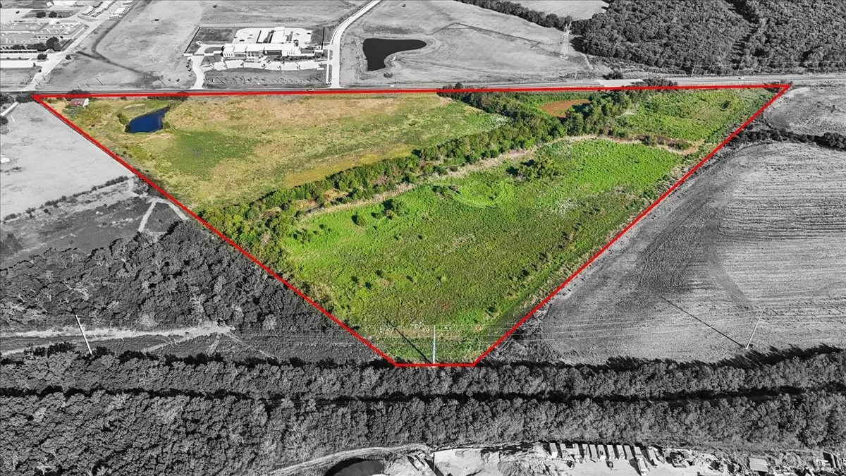 Expansive land parcel featuring open fields, wooded areas, and a visible pond