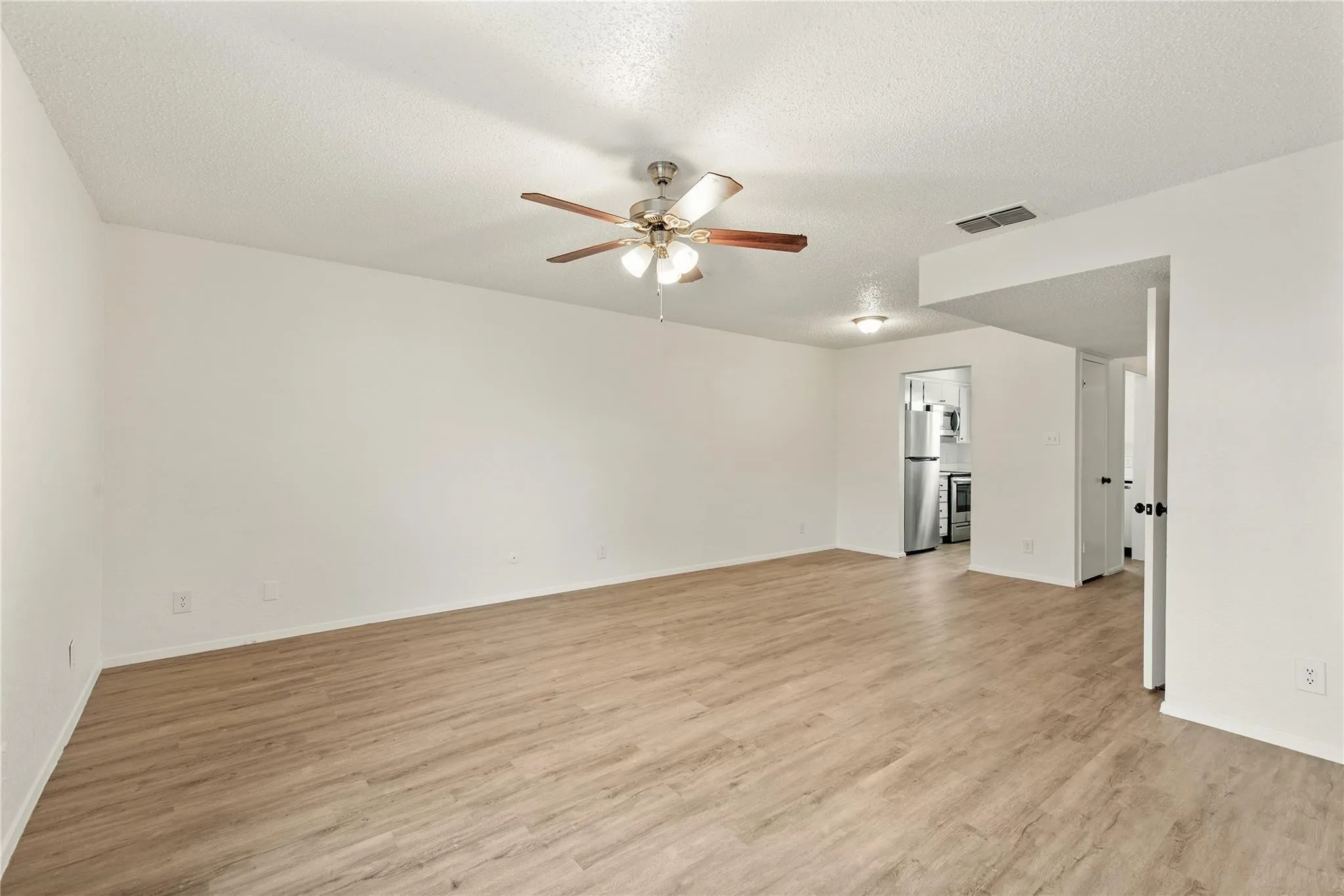 Spacious room featuring wood-finish flooring, a ceiling fan, and recessed lighting
