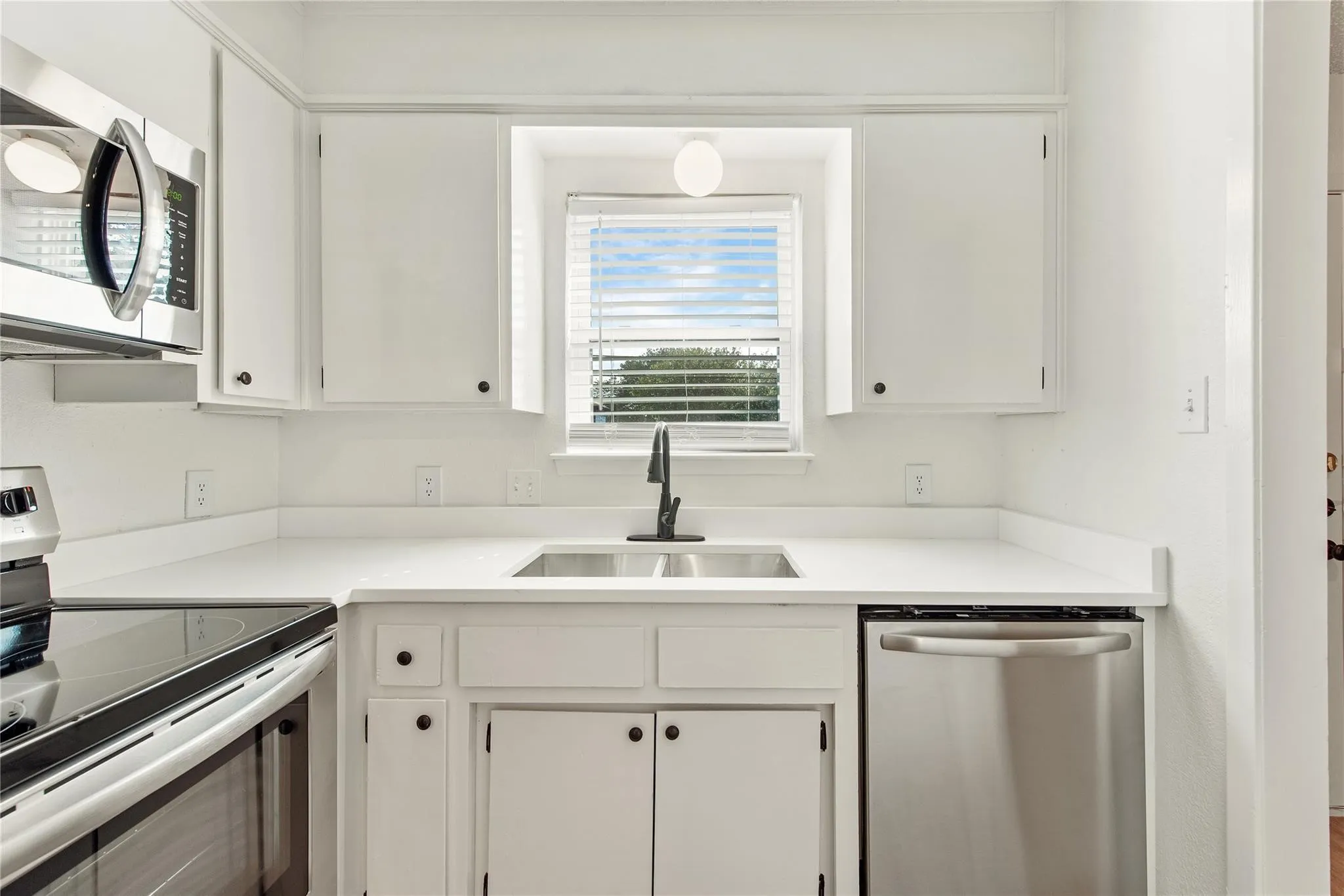 White cabinetry, stainless steel appliances, and a double basin sink