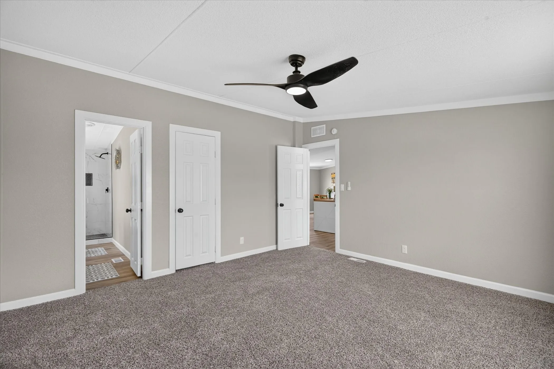 Neutral wall paint, textured carpeting, crown molding, and a ceiling fan with integrated lighting