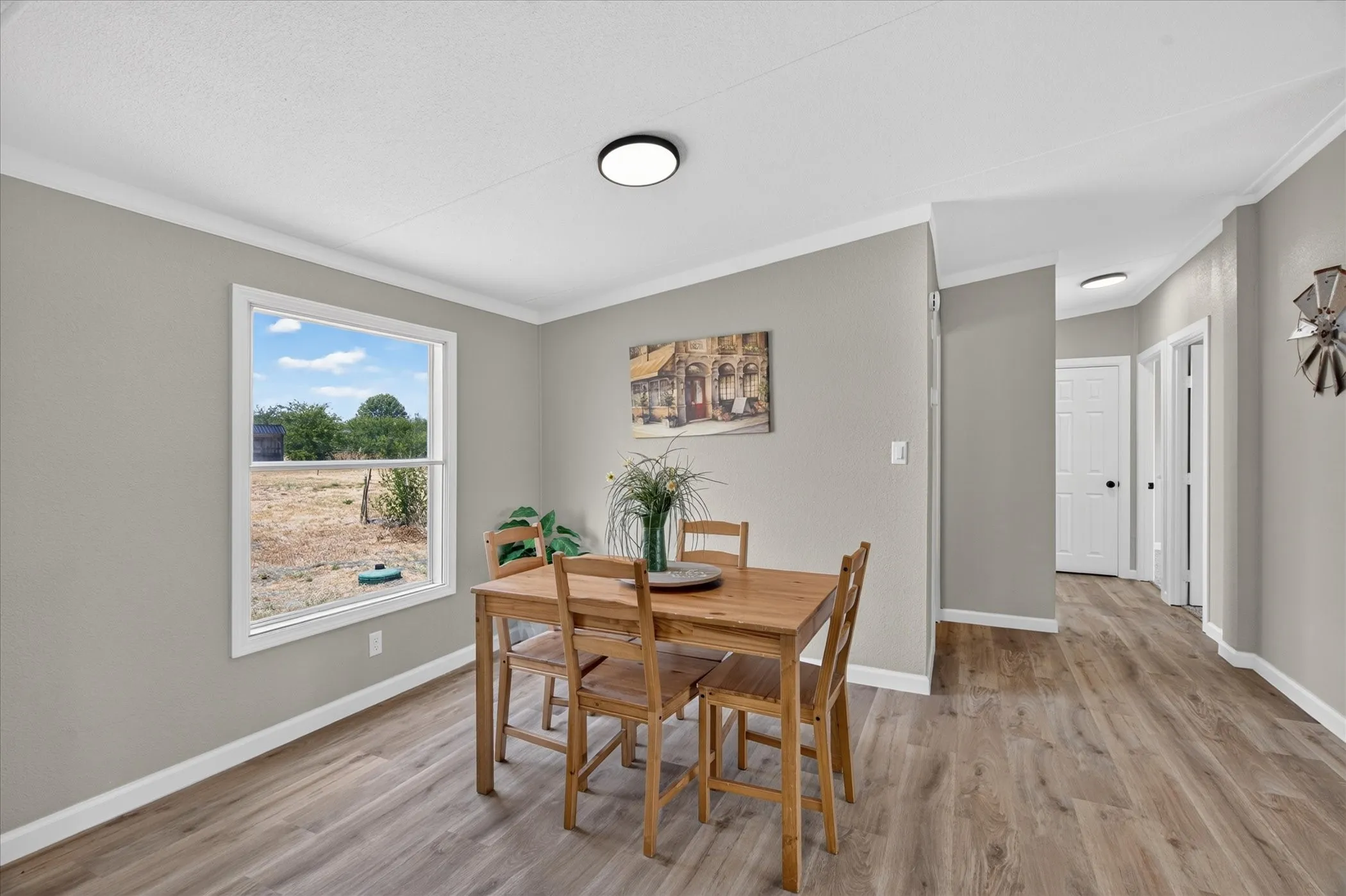 Wood-finish flooring throughout, a large window providing natural illumination, and recessed lighting fixtures