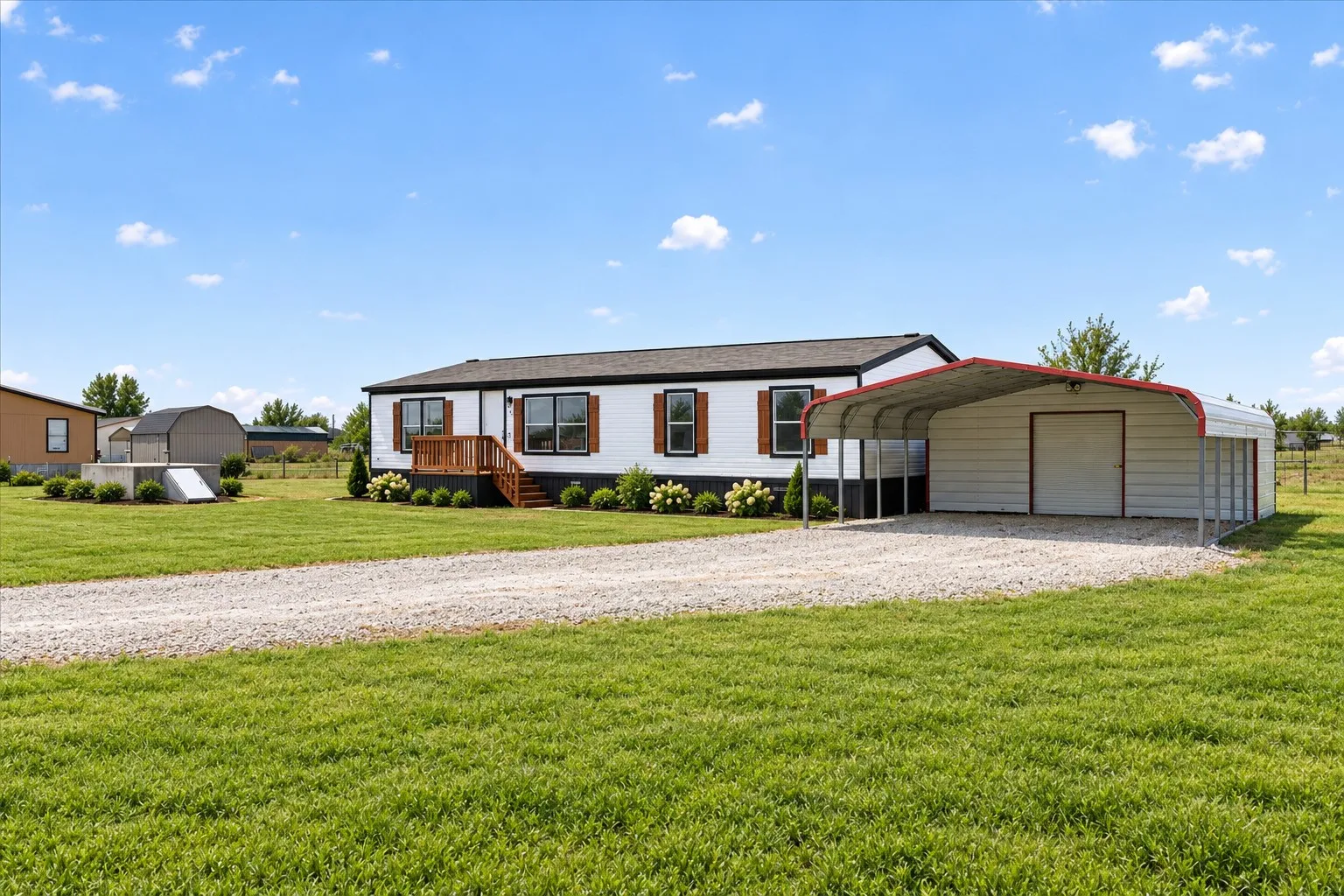 Grass and Landscape is AI. White exterior with dark trim and shutters, front porch with wood-finish steps, gravel driveway, and a detached carport structure