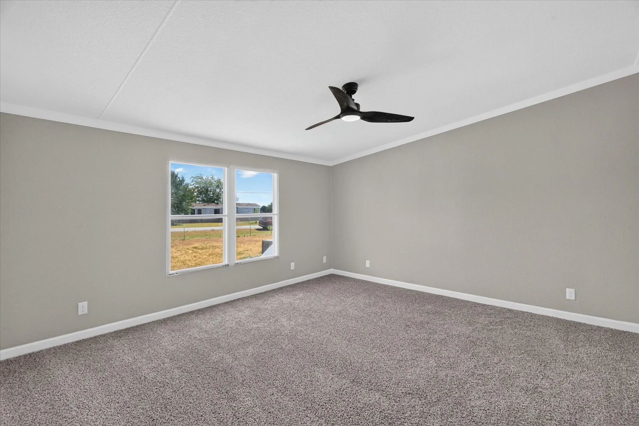 Neutral color palette, gray carpeting, dual windows, crown molding, and a ceiling fan