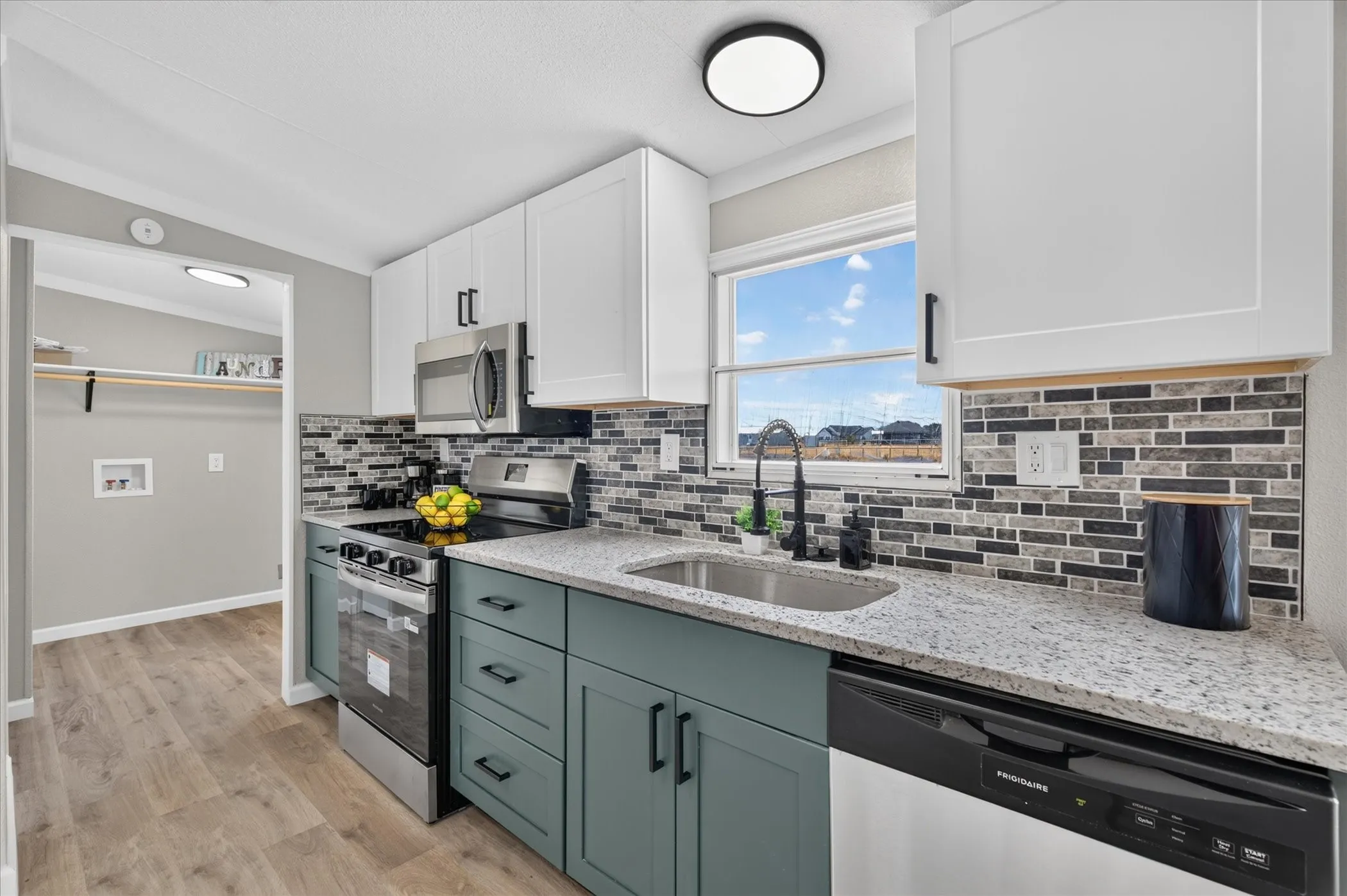 Contemporary kitchen featuring two-tone cabinetry, stainless steel appliances, granite-style countertops, mosaic tile backsplash, and wood-finish flooring