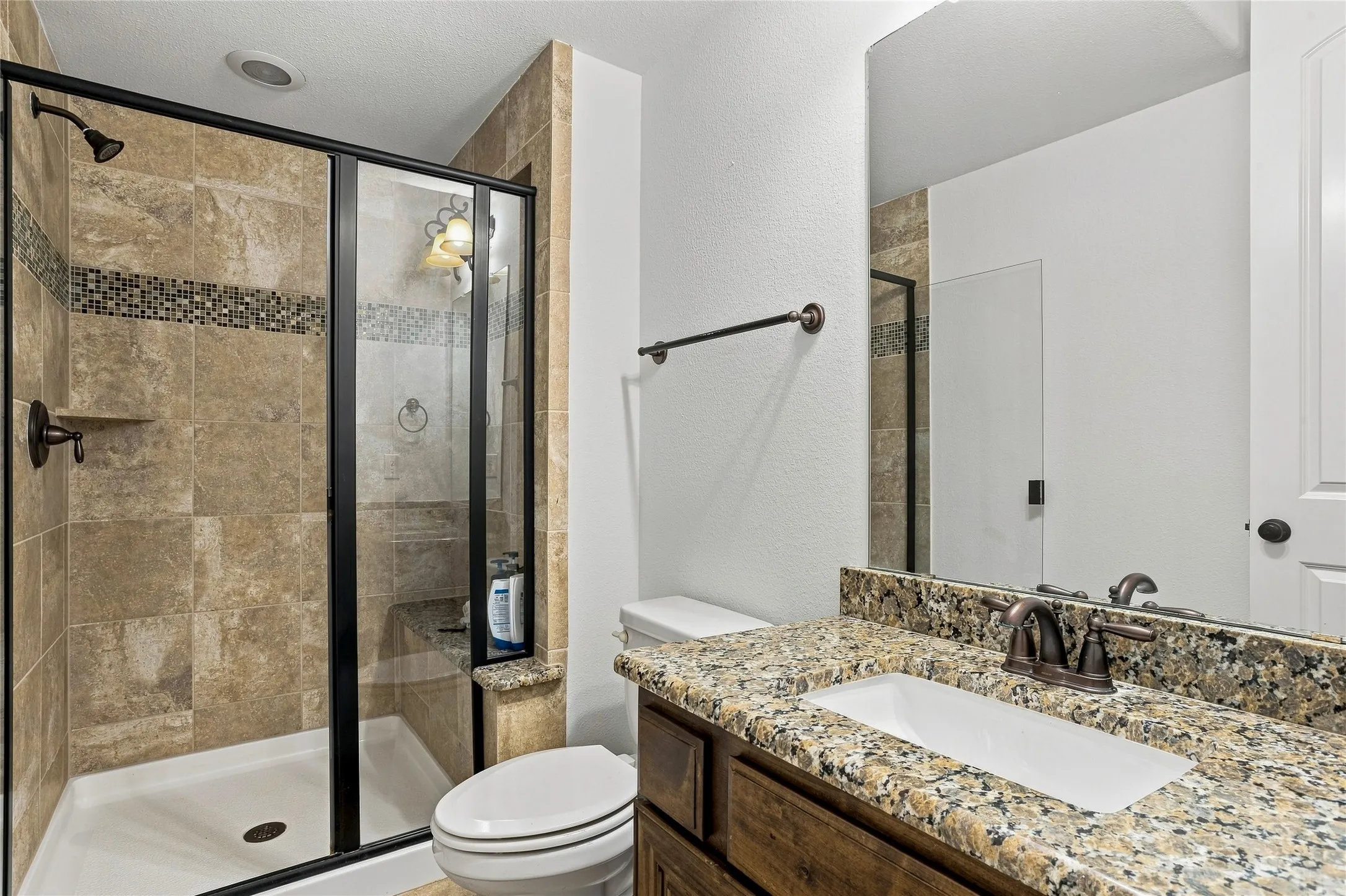 Walk-in shower with tile surround and mosaic accent