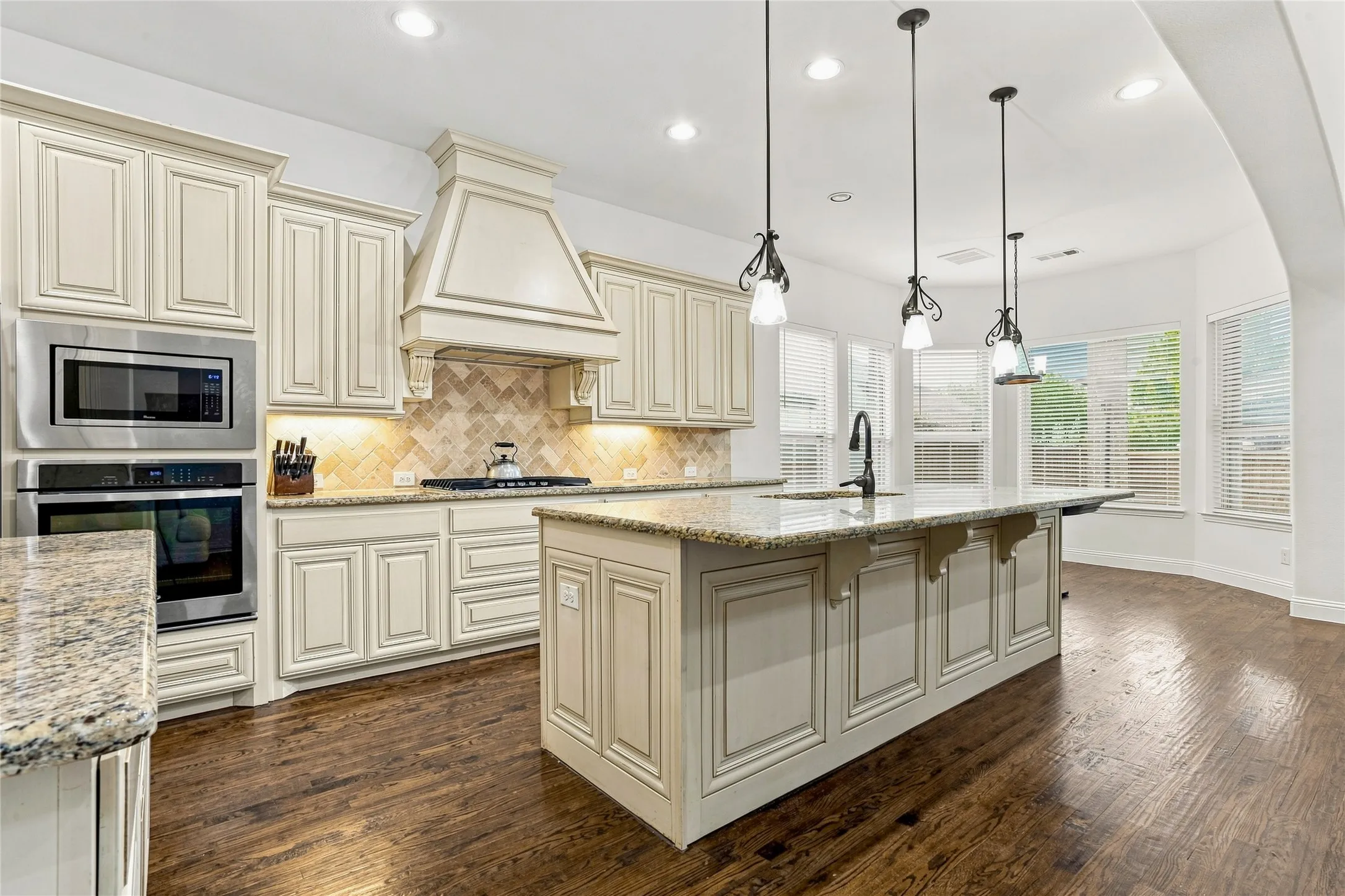 Kitchen featuring a center island with pendant lighting, built-in stainless steel appliances, extensive cabinetry, and granite countertops