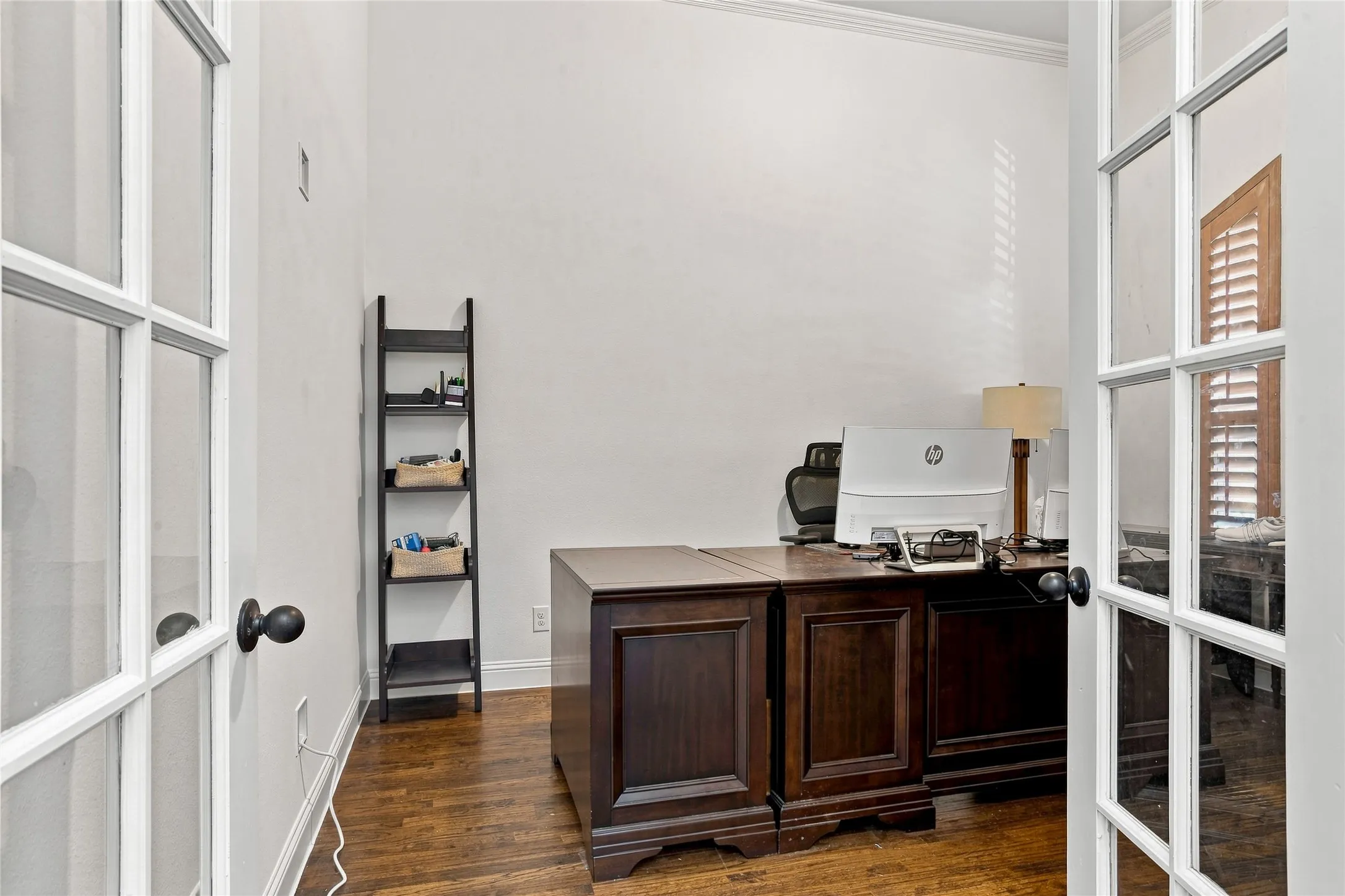 Double French doors with glass panes, wood-finish flooring, and crown molding