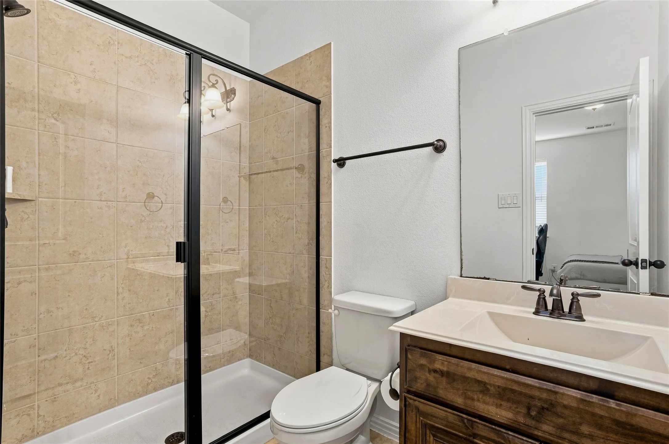 Shower with tile surround, glass enclosure, and black framing