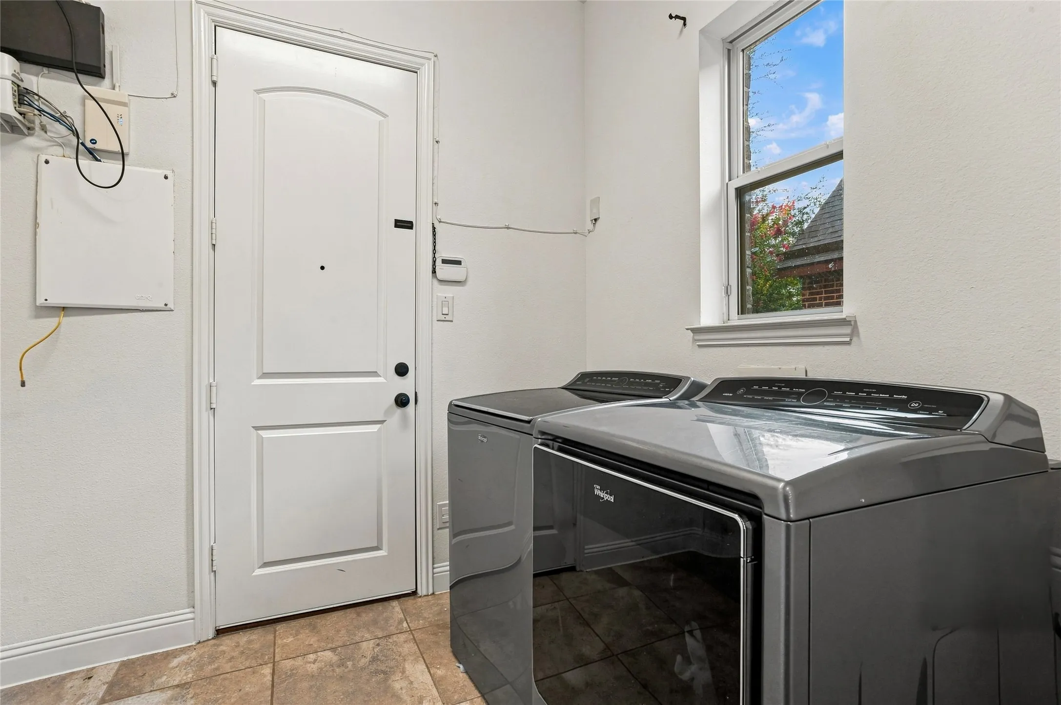 Tile flooring, white paneled door, and a single-hung window with trim