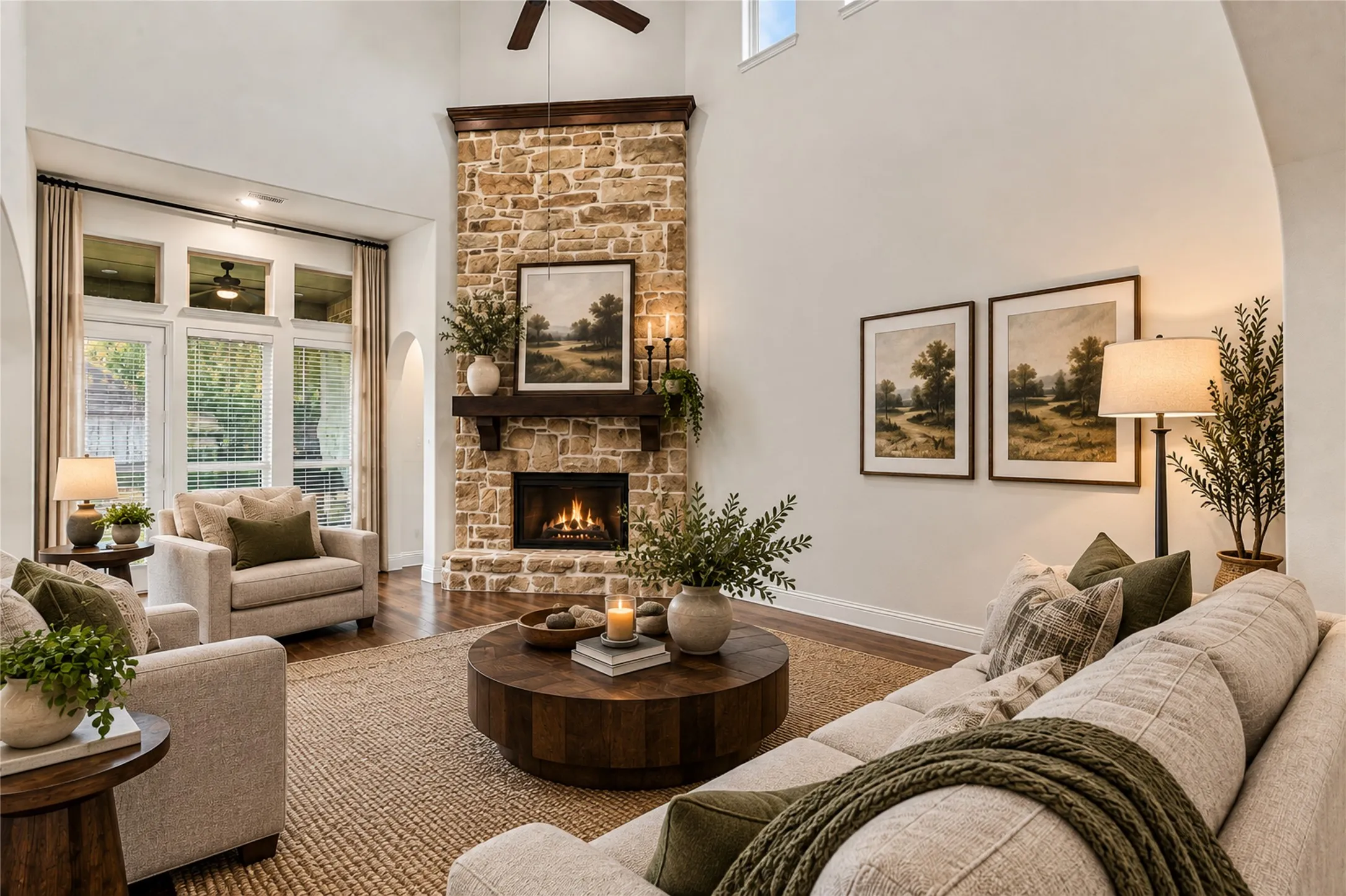 Living area featuring a stone fireplace with a wood-finish mantel, hardwood flooring, and high ceilings with upper windows