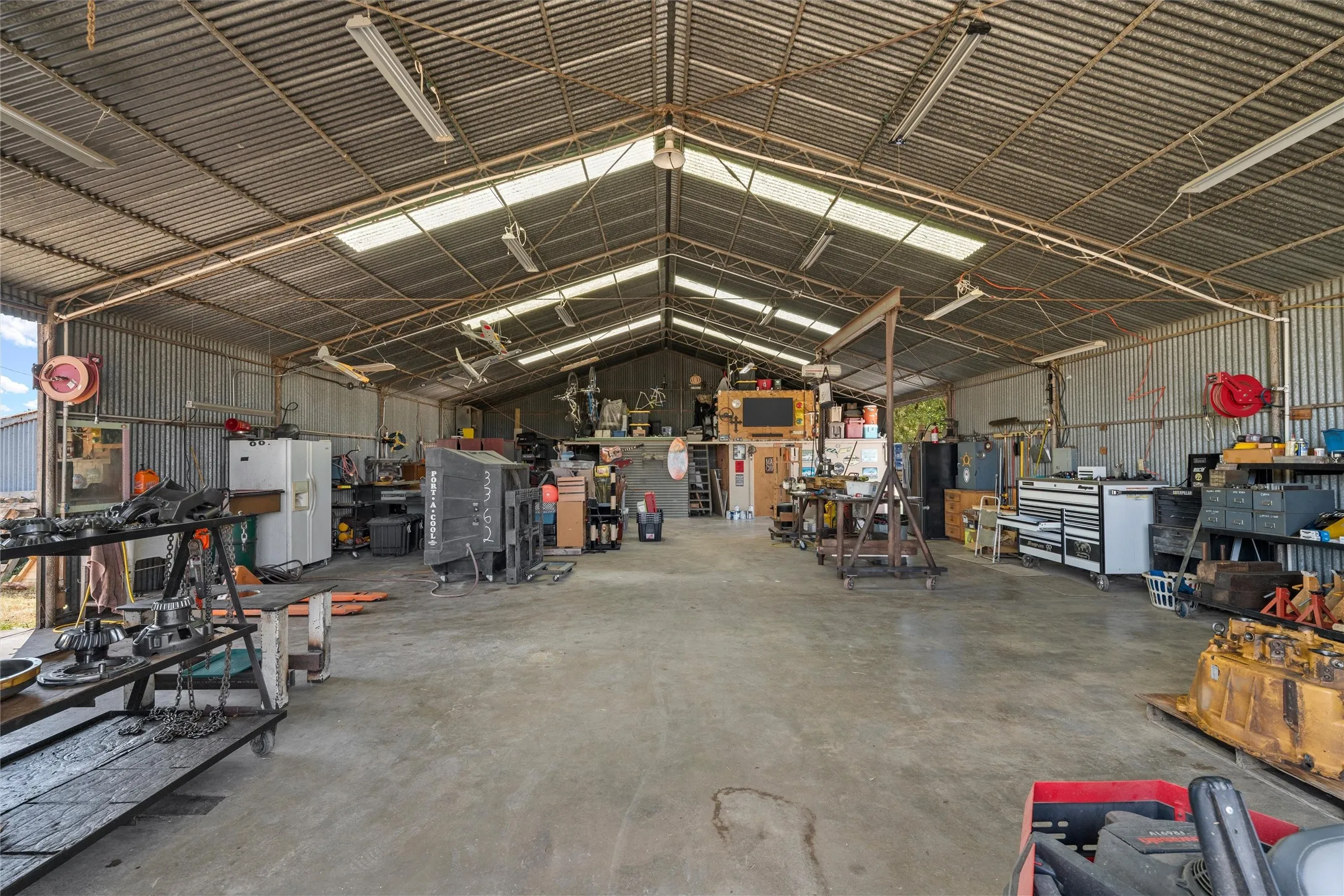 Expansive warehouse with a concrete floor, corrugated metal walls, and a high-pitched corrugated metal roof