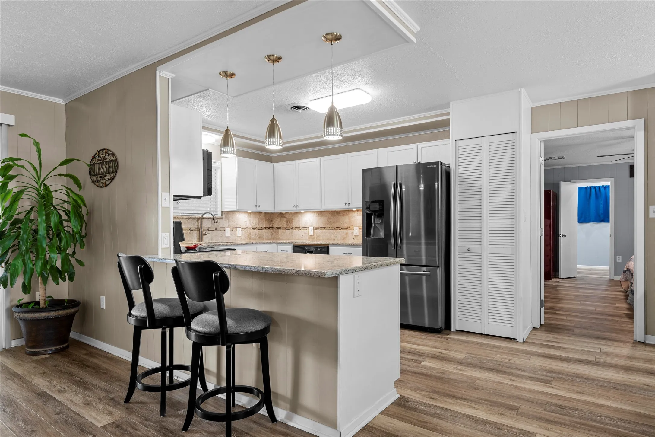 Kitchen featuring white cabinetry, a stainless steel refrigerator, stone countertops, and wood-finish flooring