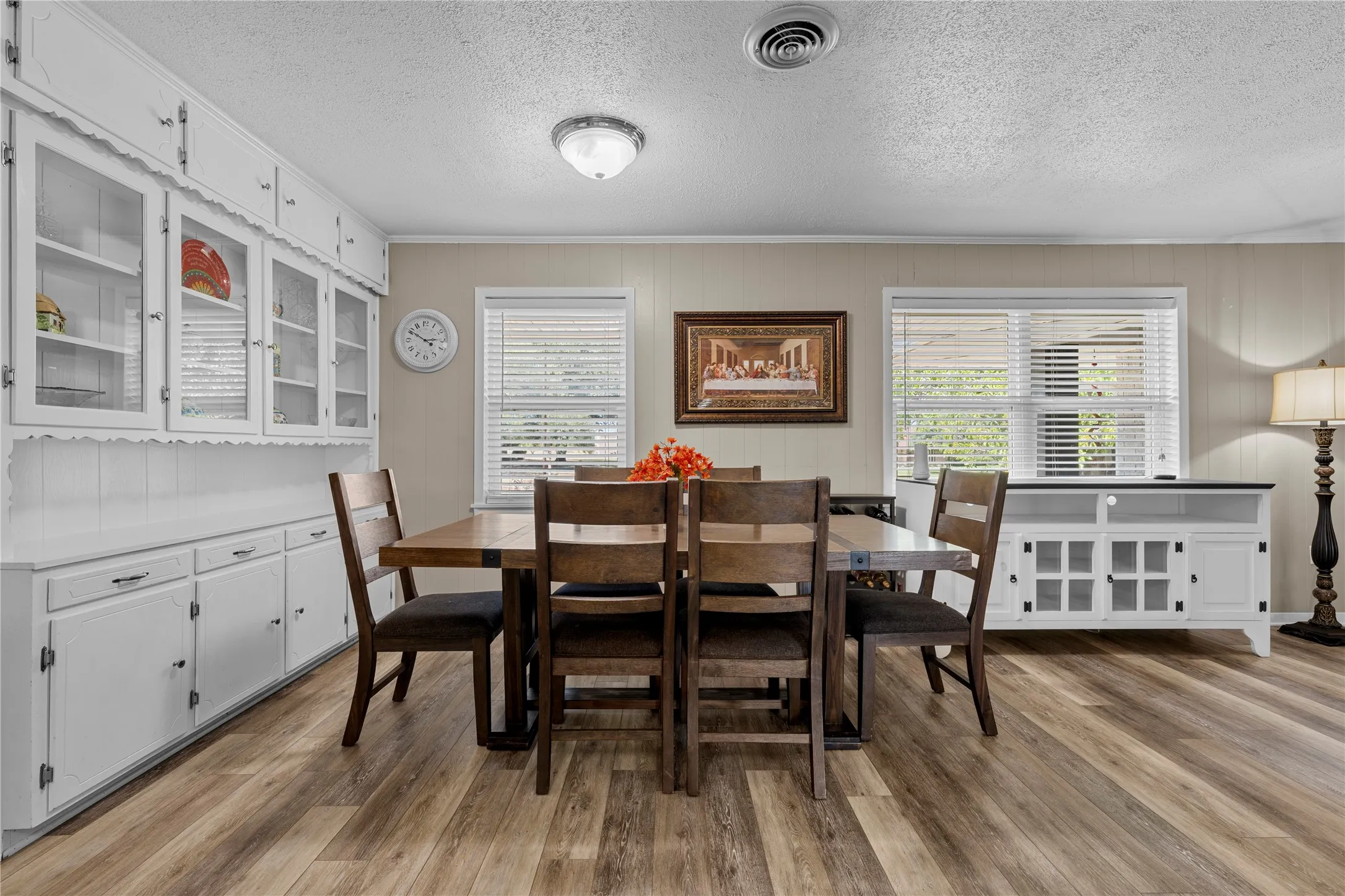 Wood-finish flooring throughout, complemented by a built-in white cabinetry unit with glass-front uppers and beadboard backing