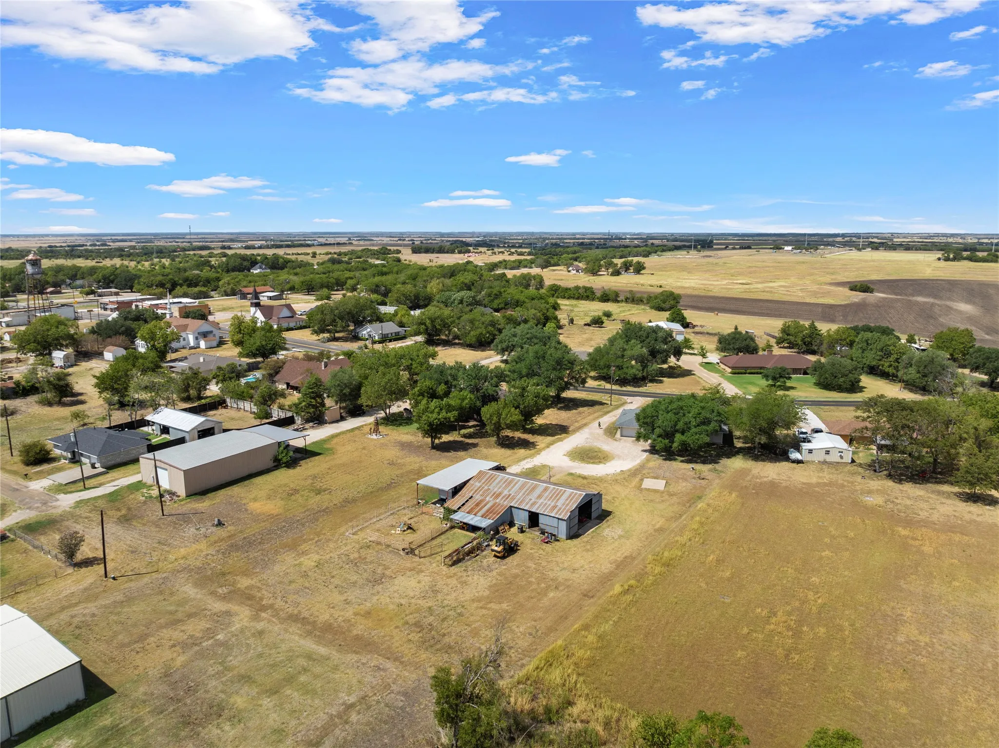 Aerial perspective showcasing multiple structures, including a metal-roofed barn and a large detached garage
