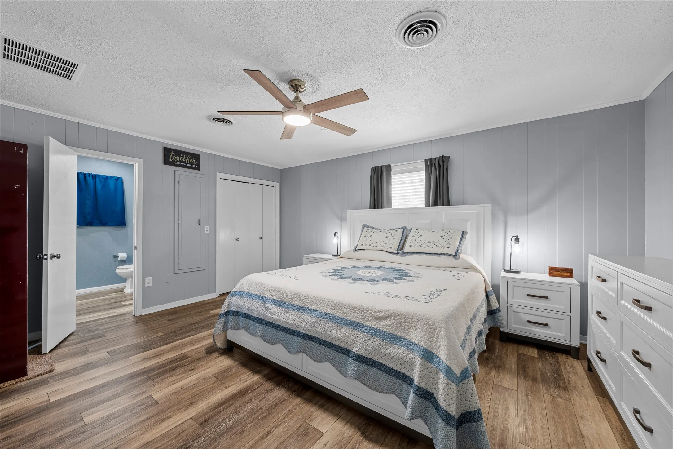 Wood-finish flooring throughout, white paneled doors, and a ceiling fan with integrated lighting