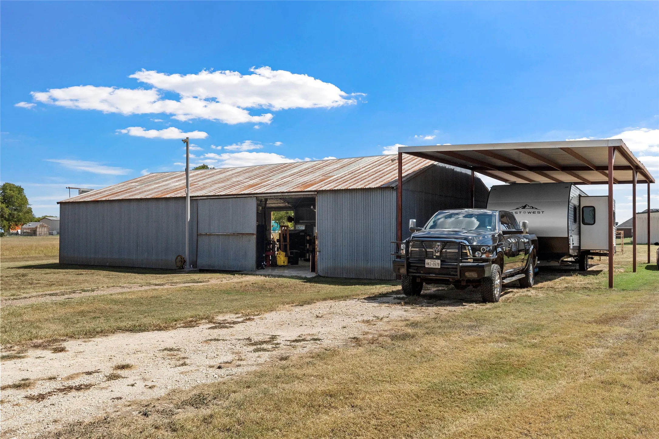 Corrugated metal barn with a sliding entry door, featuring an attached metal carport structure