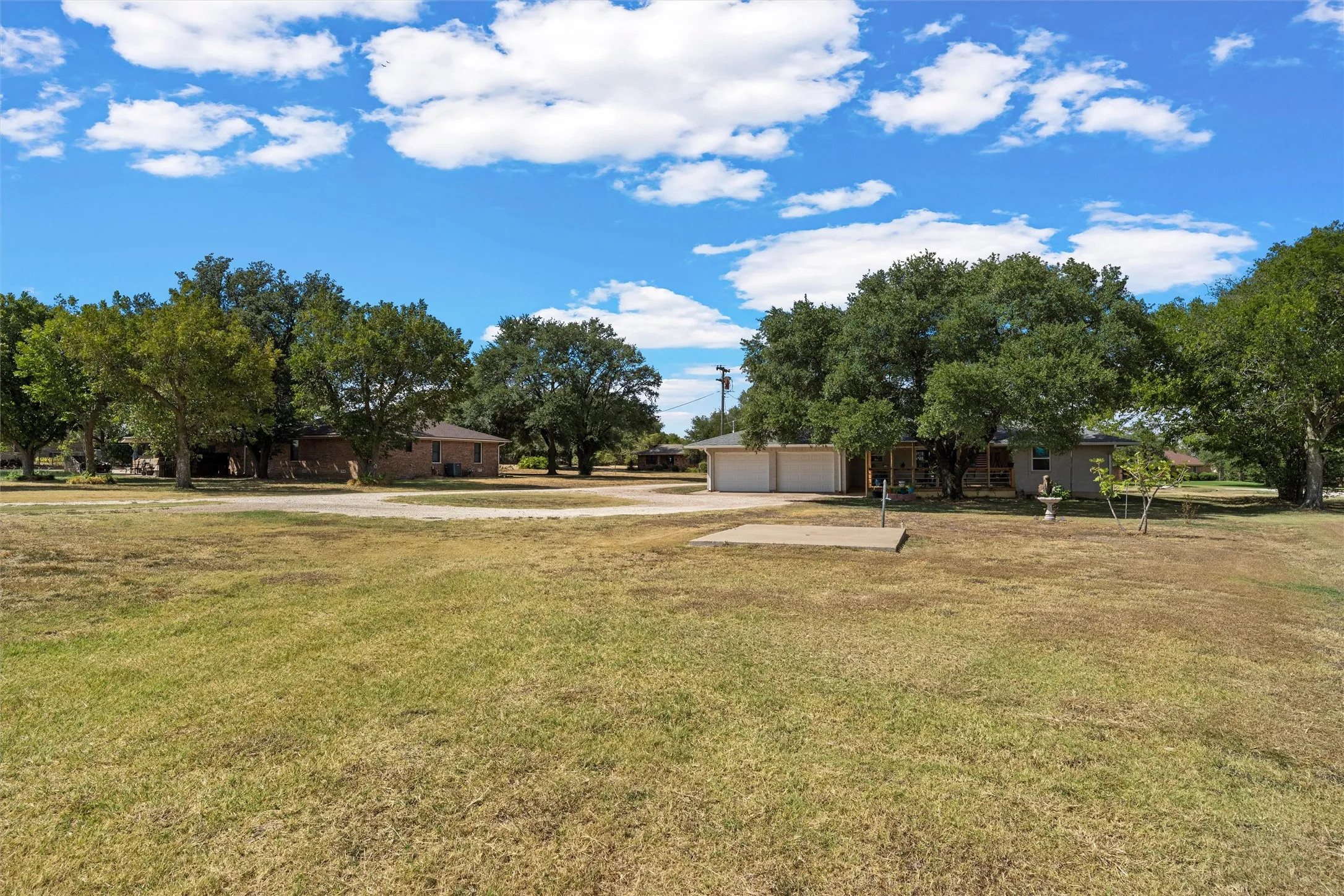 Expansive lot with mature trees, a two-car attached garage, and a brick exterior home