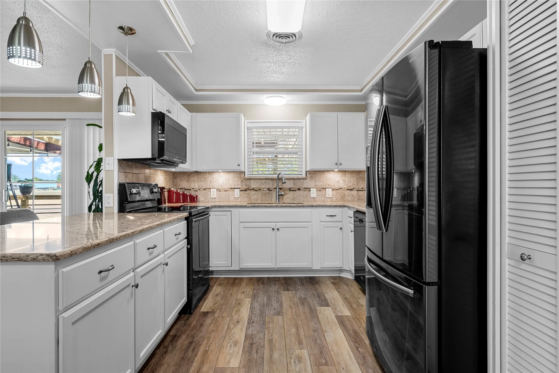 Kitchen featuring white cabinetry, wood-finish flooring, undermount sink, stone countertops, and a tiled backsplash
