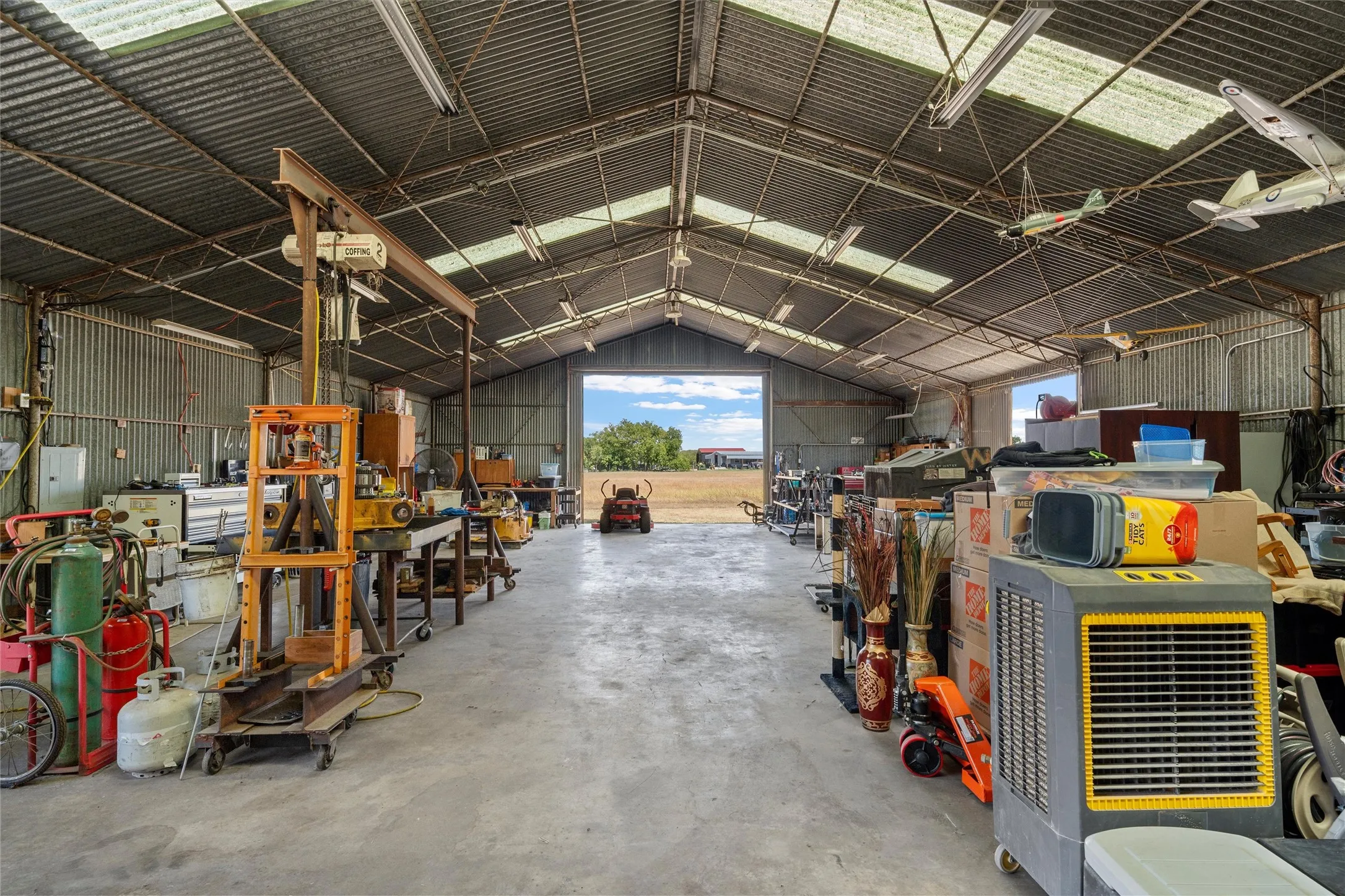 Spacious metal-frame structure with a corrugated metal roof, translucent roof panels, and concrete flooring