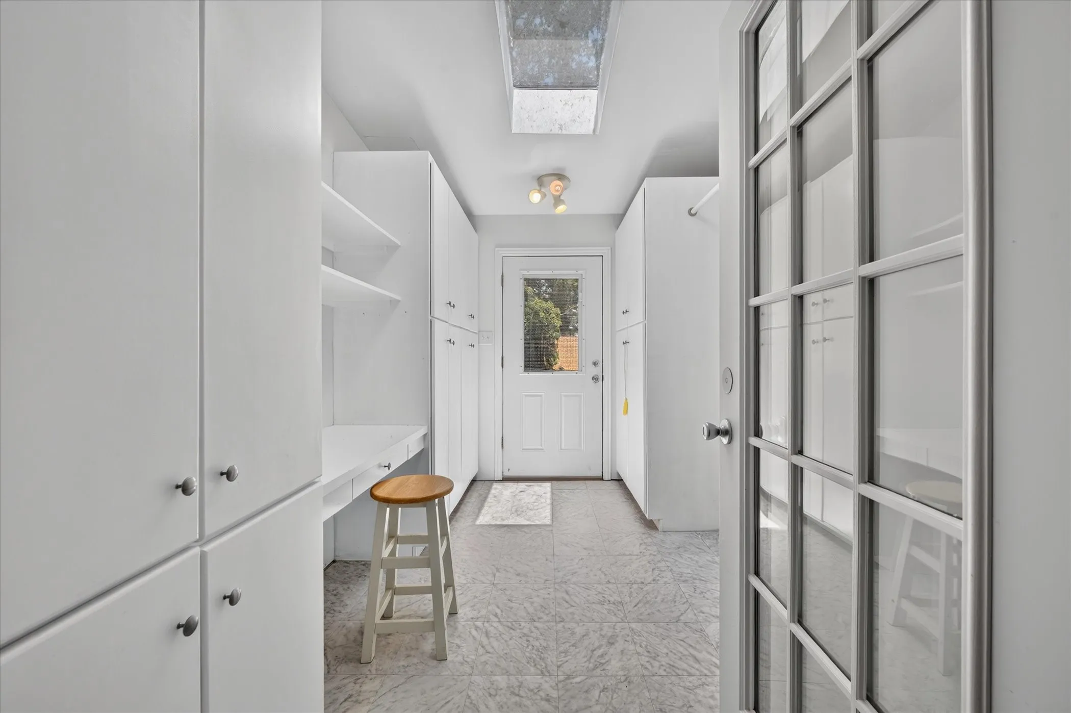 White cabinetry with integrated desk, open shelving, and a skylight