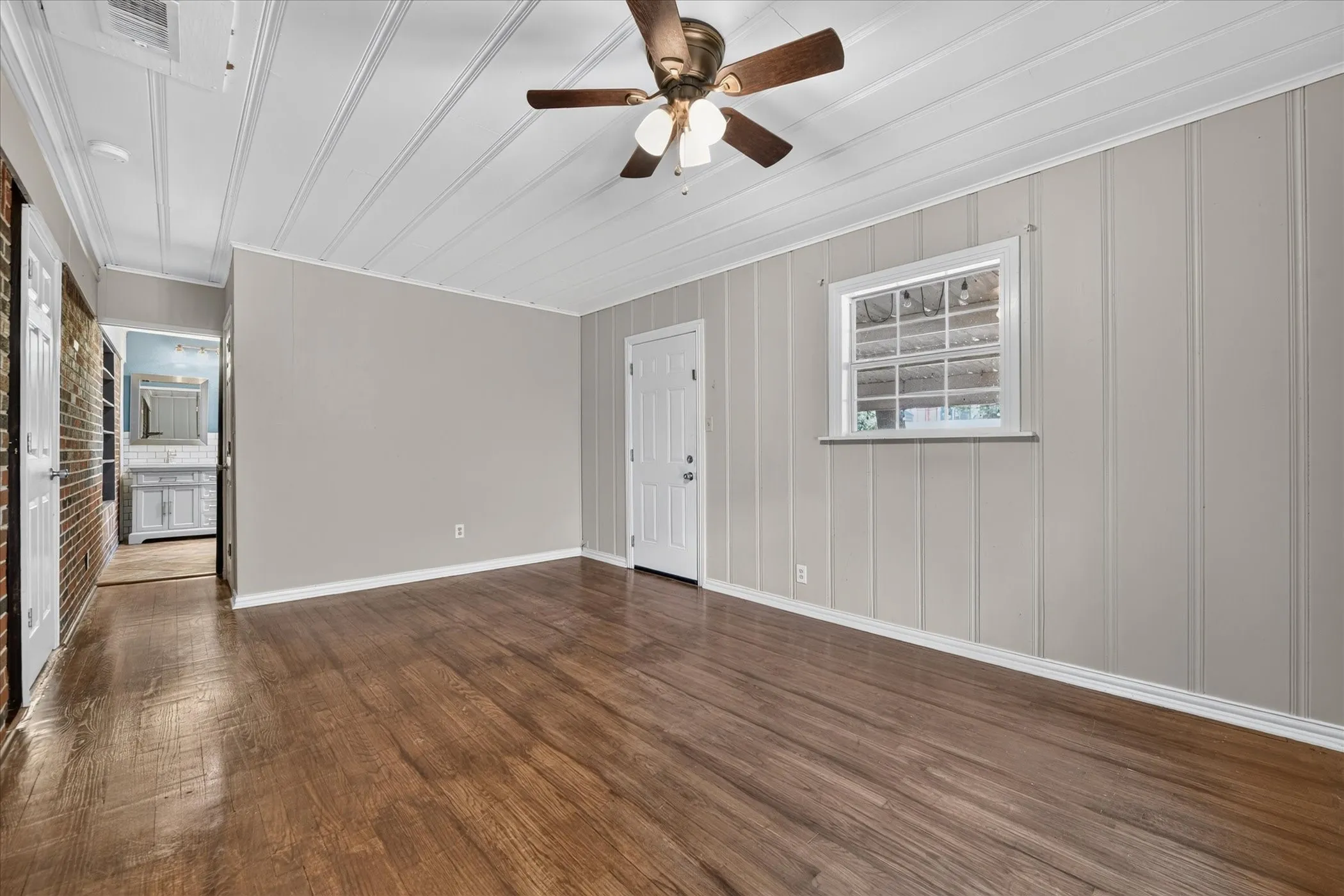 Wood-finish flooring, white paneling, ceiling fan with light fixture, and a single window