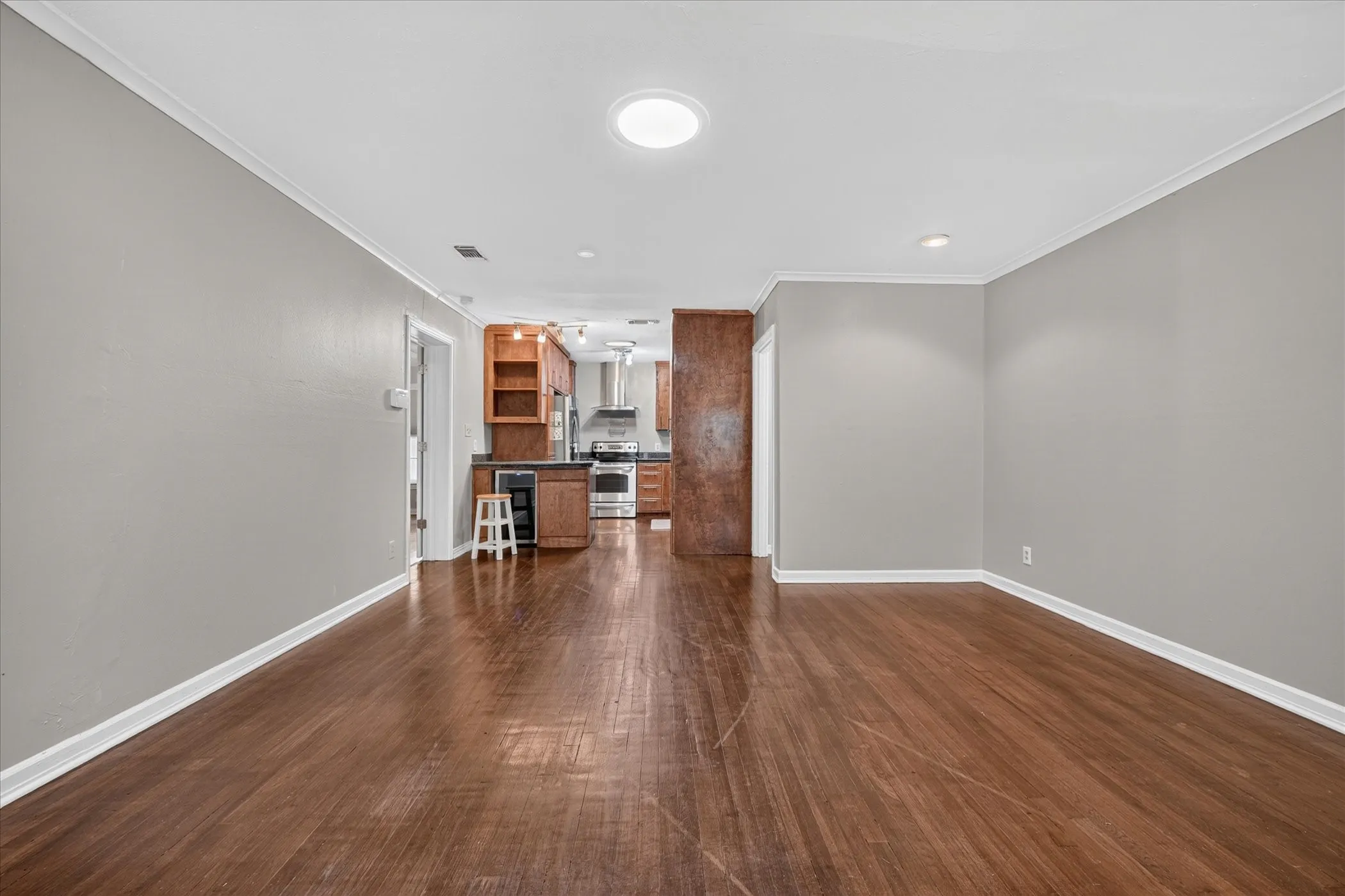 Wood-finish flooring throughout, light gray wall finishes, recessed lighting, and a circular flush-mount ceiling light